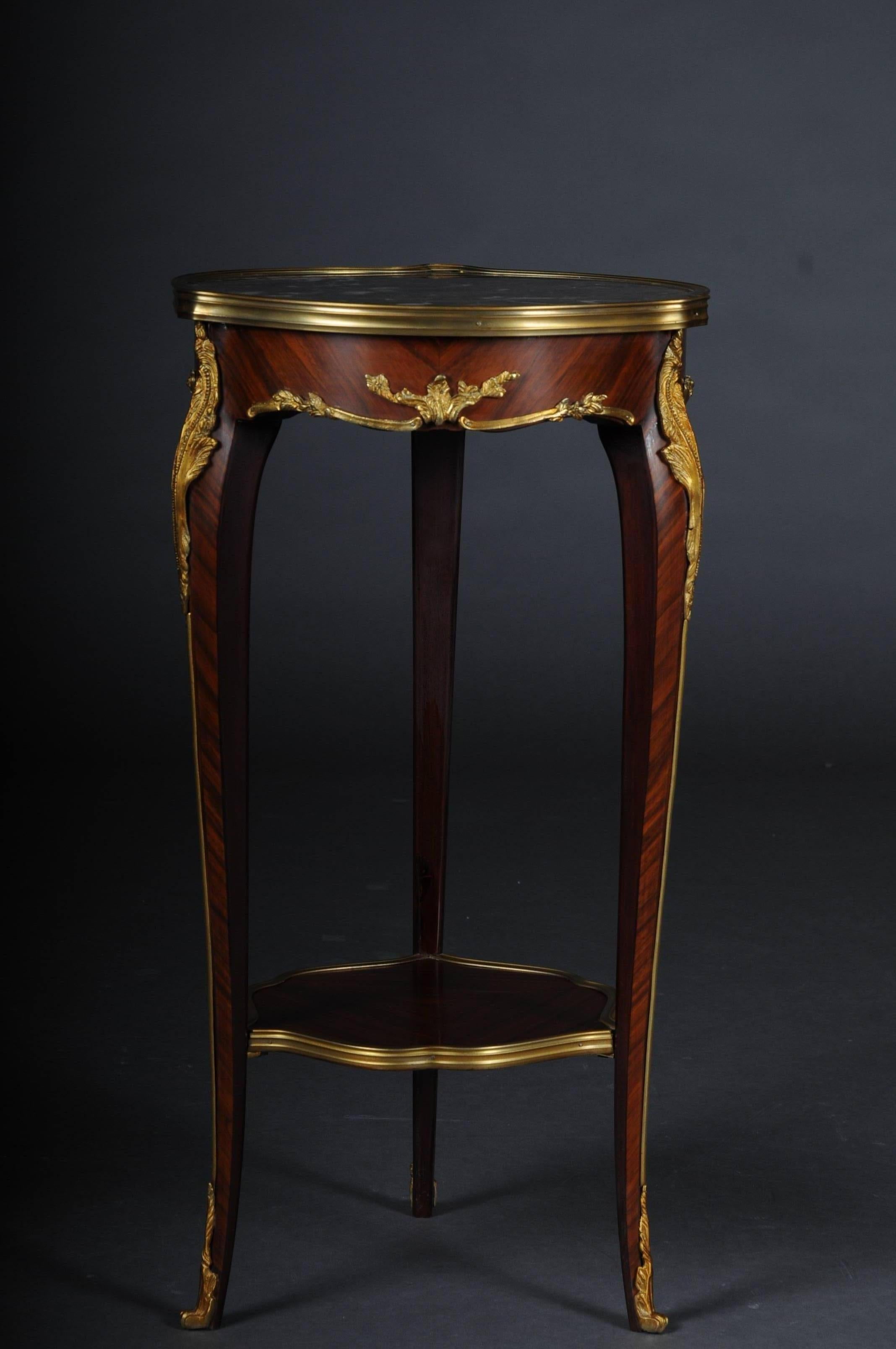 Solid wood side table in Louis XV. Slightly convex and concave, carcass, flanked by solid corner glaciers on high, elegantly curved legs, connected below by a curly brass frame framed by an intermediate shelf, ending with bronze fittings in