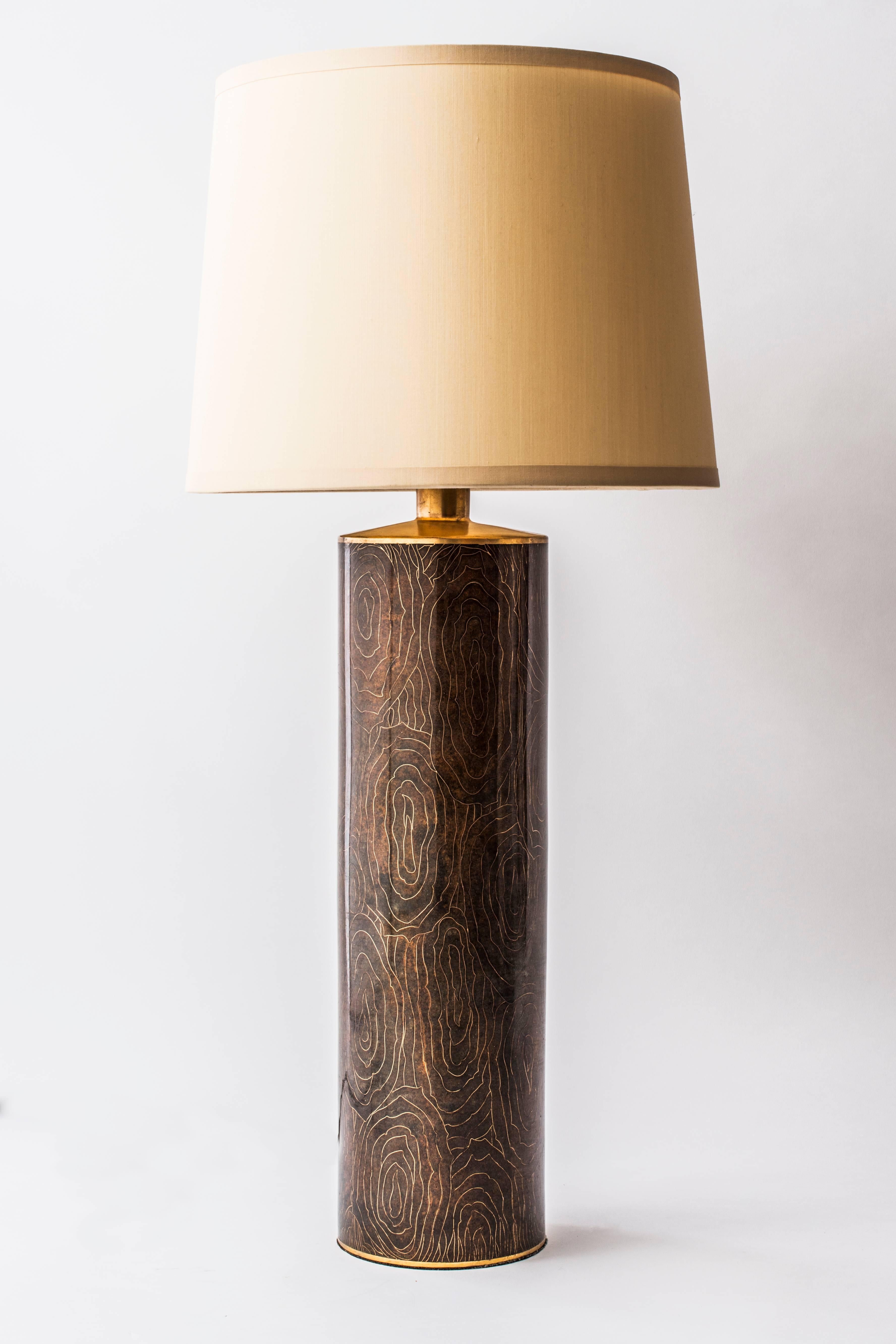 This stunning cylindrical table lamp features a faux wood grain design, created by cloisonne comprised of 24-karat gold-plated coils and trim, filled with a warm, natural, amber toned enamel. Created by Robert Kuo for McGuire.