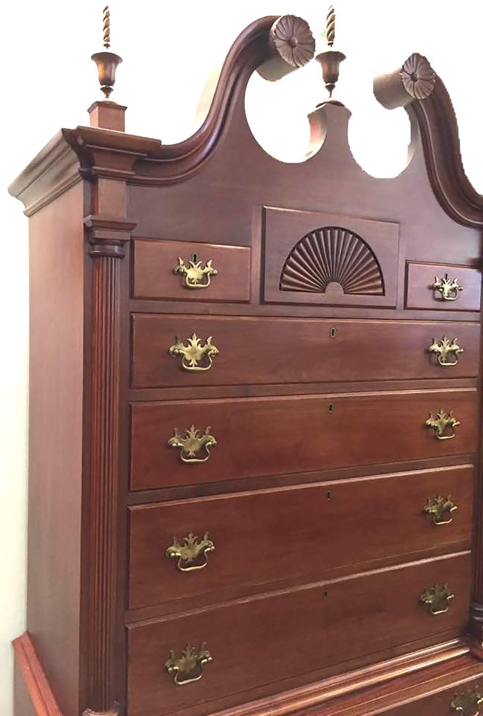 Mahogany highboy attributed to Kittinger. Top piece has carved finials, carved shell, and carved flowers. Six drawers with brass decorative handles. Bottom piece has three drawers with another carved shell. Four legs lead into a ball-and-claw