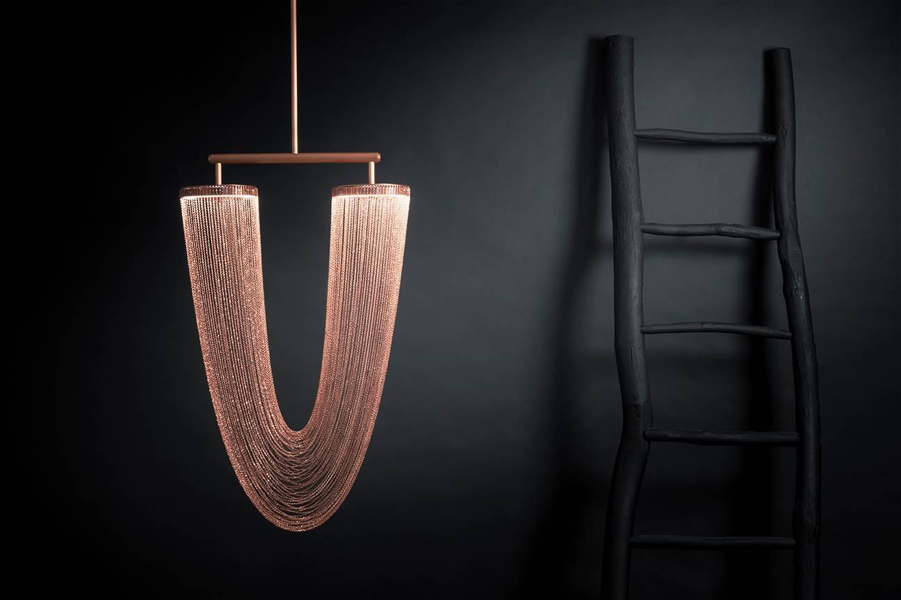 Otero is a luxurious high-end lighting fixture that has been coated with warmth and elegance.This sculptural light is handcrafted with delicate copper chains to create a unique and elegant curved shape inspired by the romantic world of jewelry. The