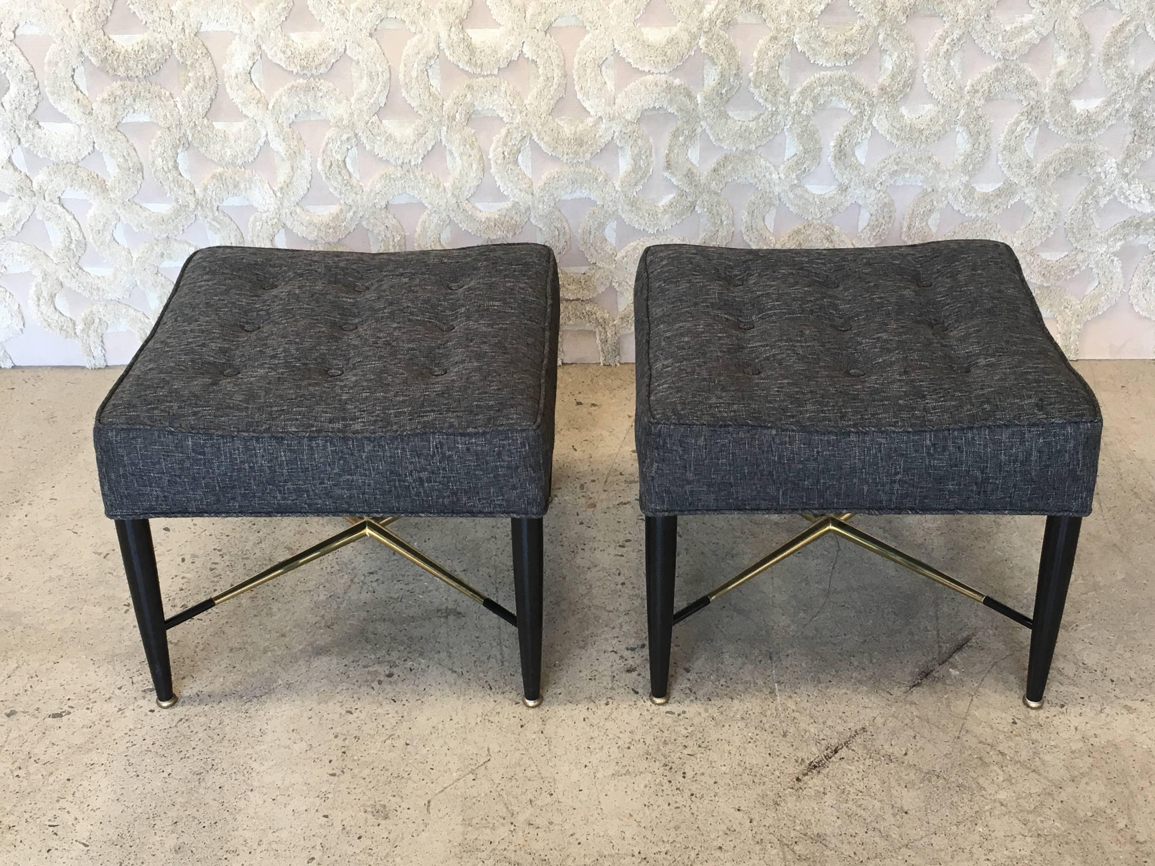 Pair of tufted Mid-Century ottomans ebonized with polished brass stretchers.