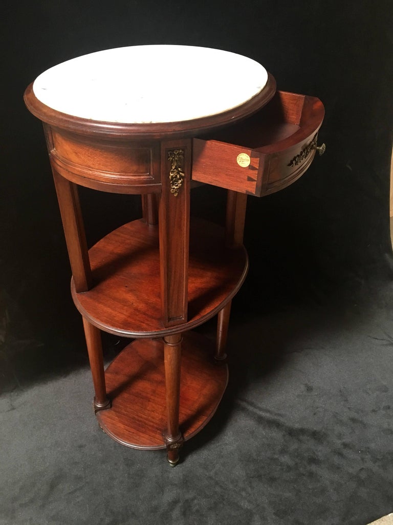 This antique table could be used as a nightstand or plant stand
Solid mahogany with bronze ormolu mounts and white marble top.