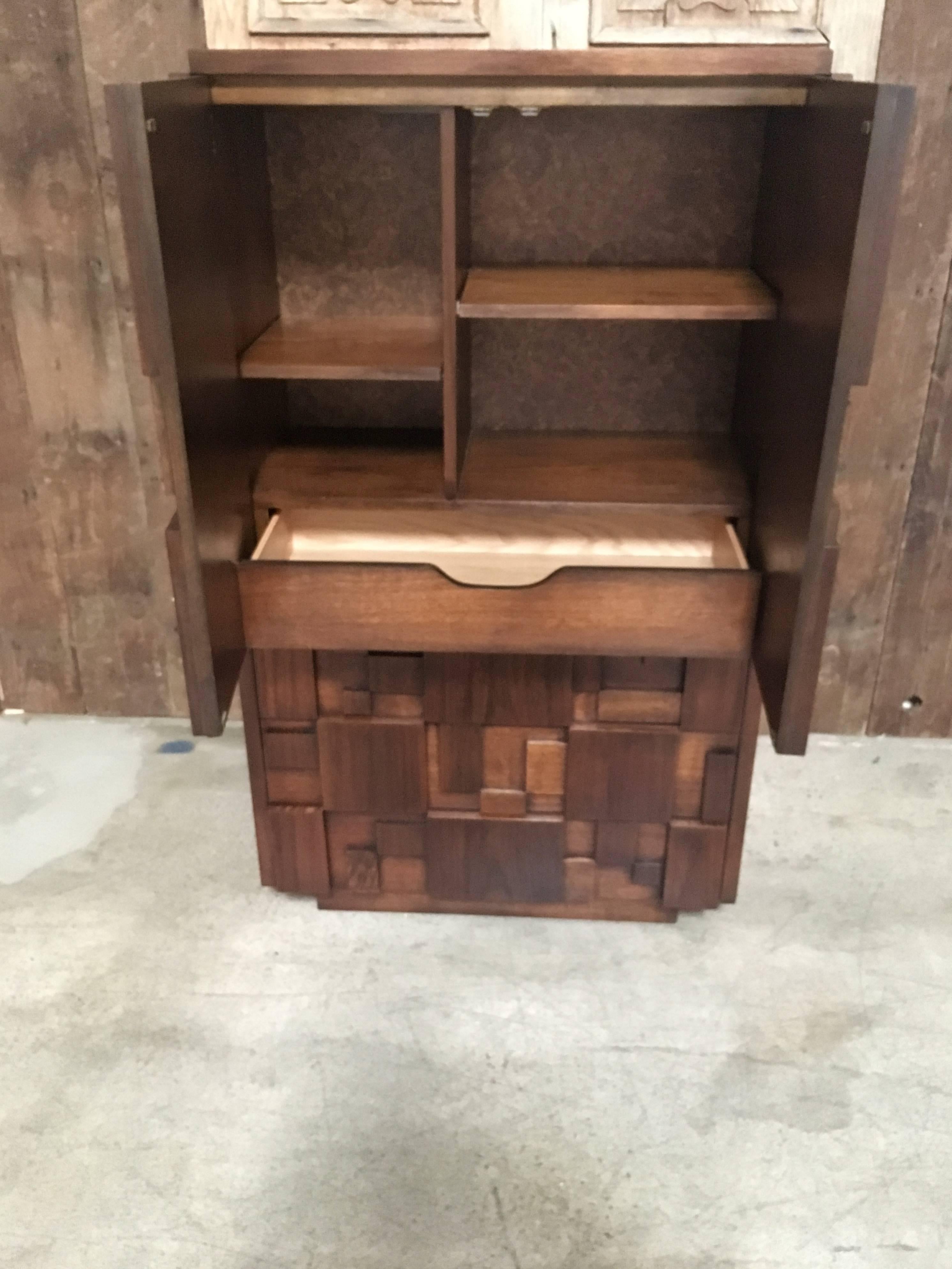 This Geometric design dresser / armoire with three drawers at the bottom and shelves inside the top section for maximum storage 
a combination of wood veneers walnut, pecan, ash.