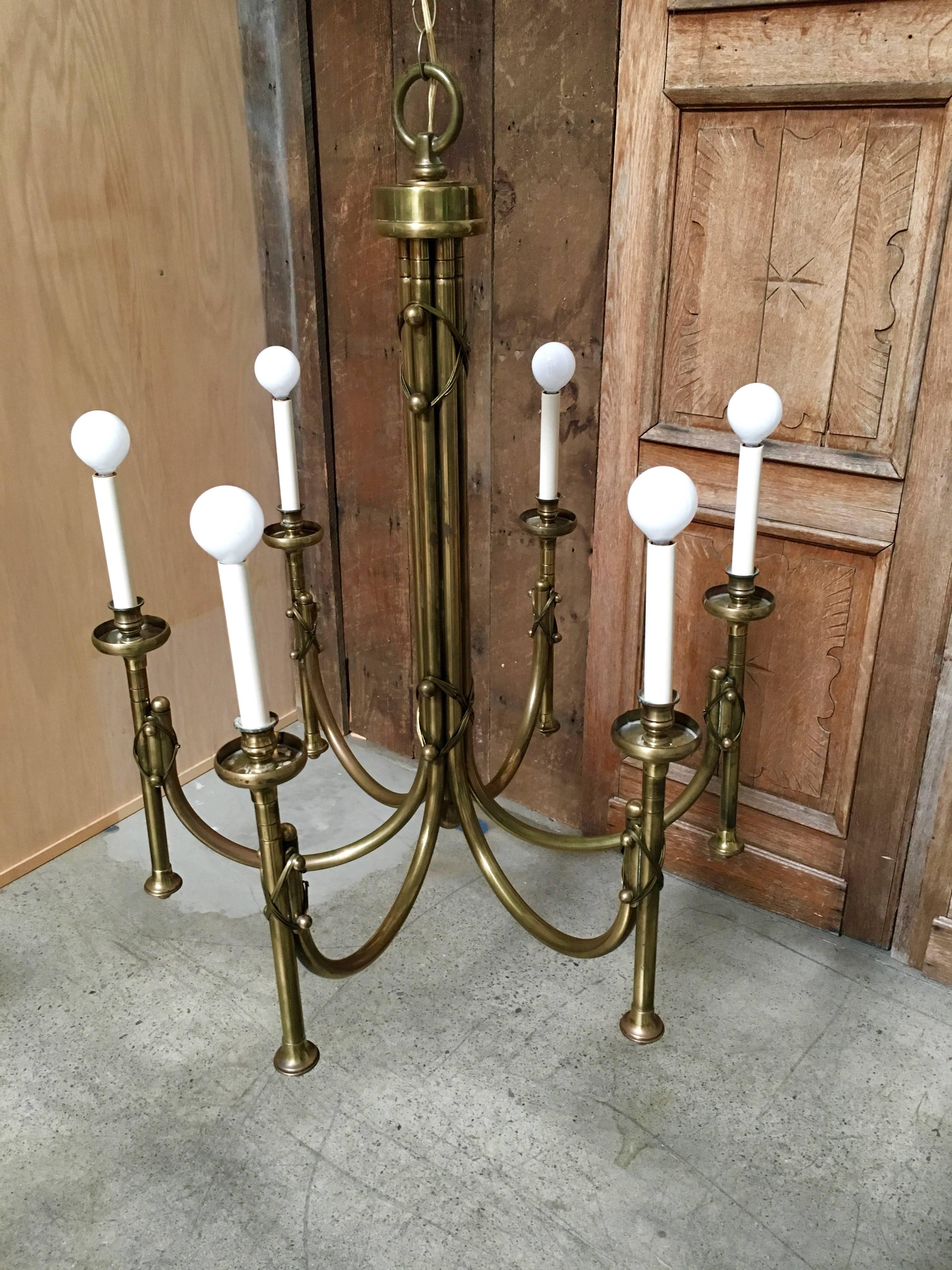 This is a great solid brass chandelier with X strap fasteners on the centre column and the six arms. There seems to be a little Tommi Parzinger flair to this piece.