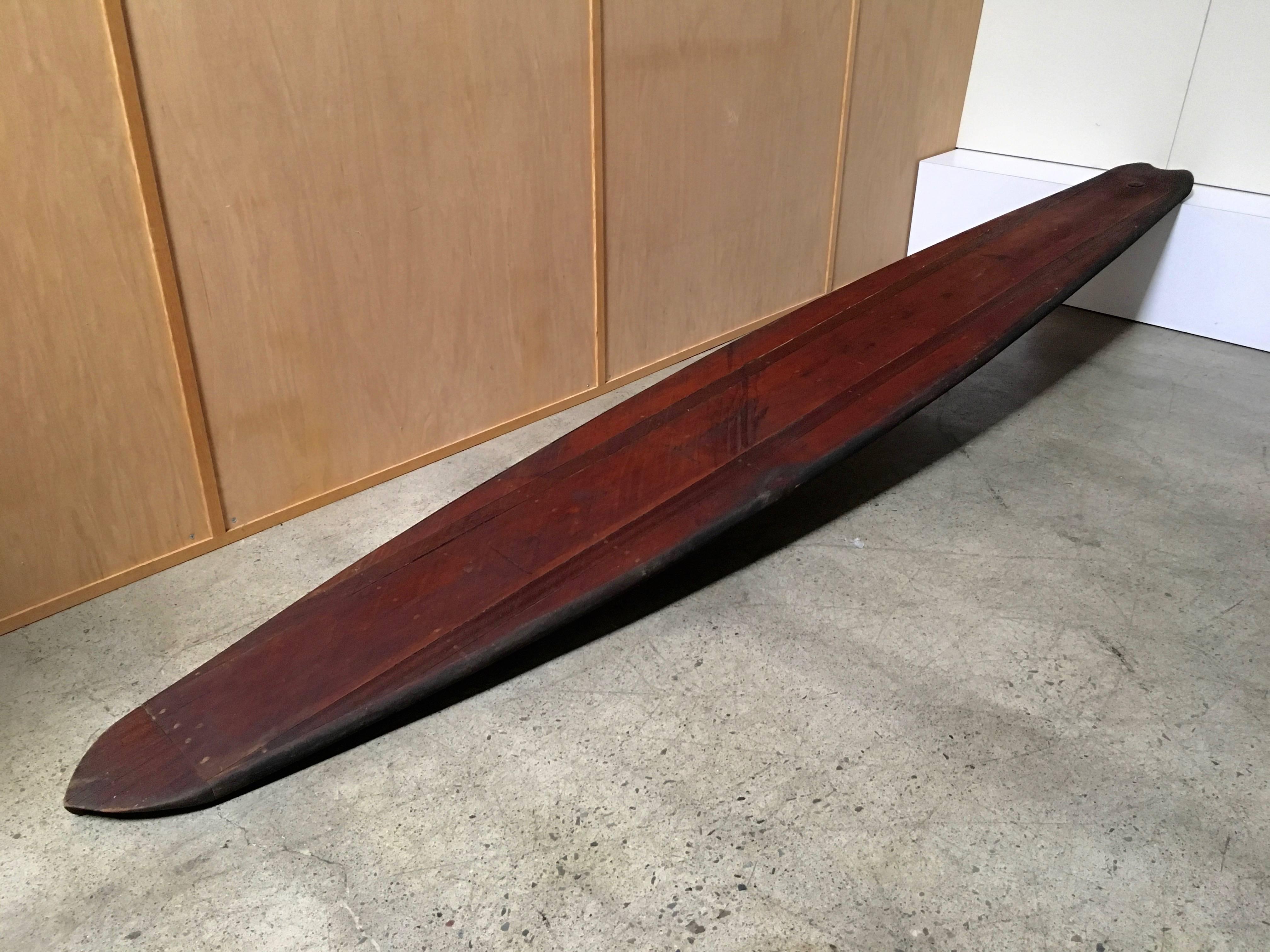 This early paddleboard is a hollow wood board made of Mahogany and redwood with a dove tailed back end.