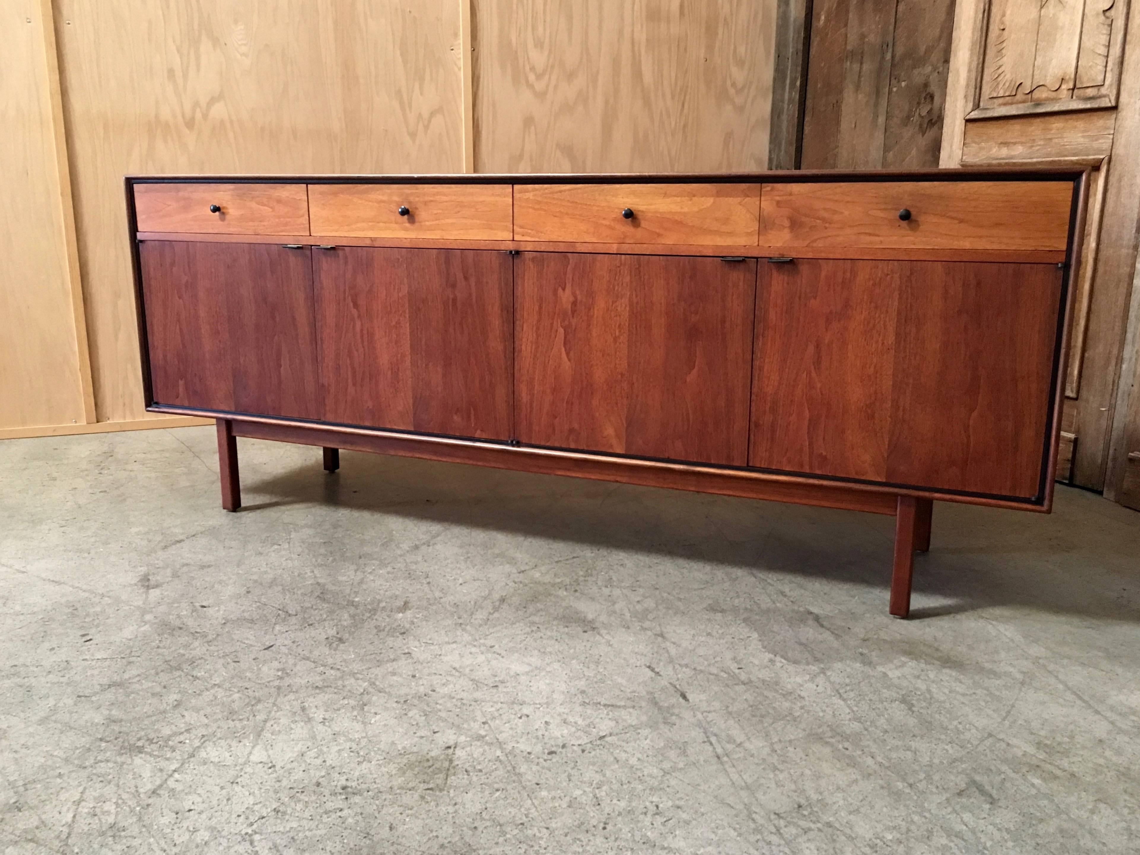 Large four-drawer over four-door walnut credenza with dividers in two of the drawers for flatware and shelves inside the doored section with black leather door pulls.