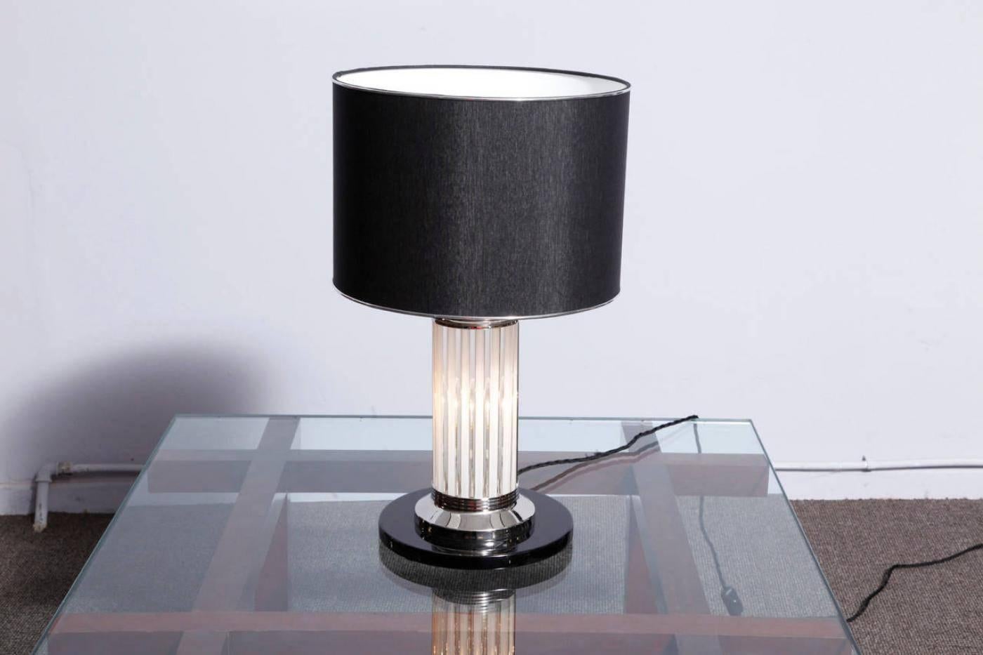 A nicely designed pair of Art Deco lamps designed in the spirit of Atelier Petitot, France.
Black lacquered wooden base with nickel plated metal elements, glass tubes running from the base to the black colored shade. Two electric bulbs were placed