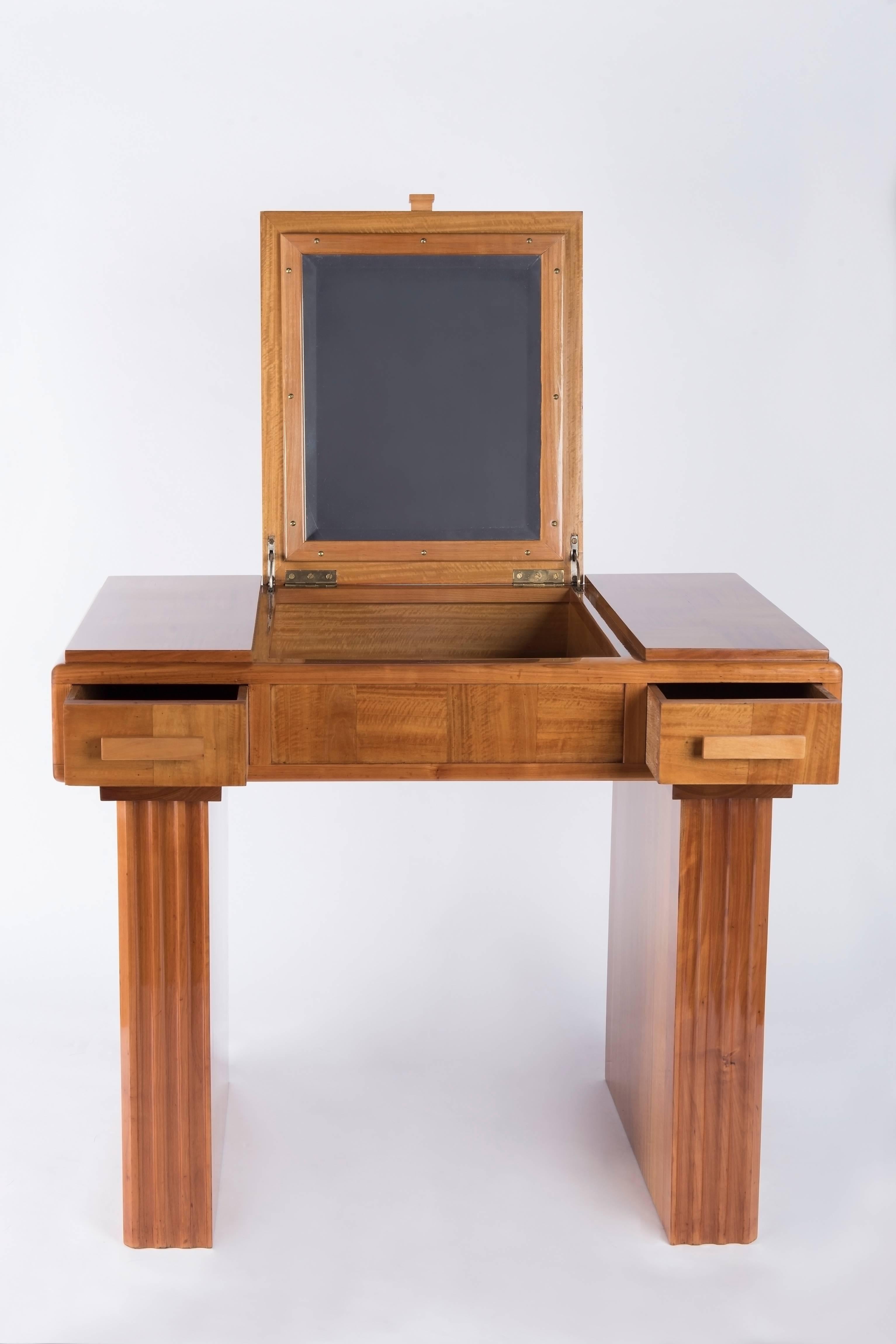 1930s lemonwood veneered French origin art-deco vanity. It can be used as well as a small desk .
Top opening to a small cabinet, mirror inside of the top. Two drawers,one on each side. Wooden handles. Small shelves on both sides. Veneered and