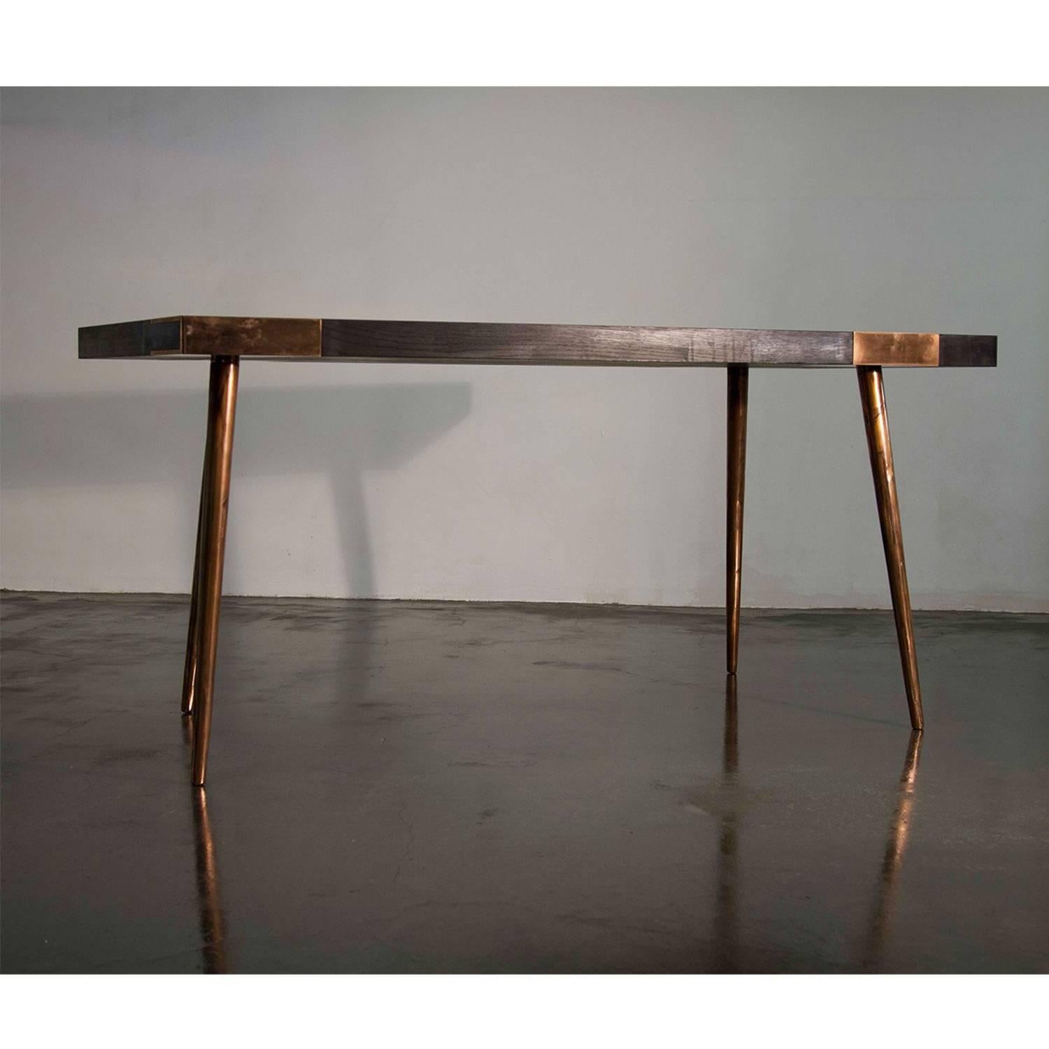 Indigo is a handcrafted stylised walnut or oak veneer and coppered steel or patinated brass finish dining table with classic in-kitchen dining proportions. The table's legs are offered in several finishes - silver plated, brushed brass, polished