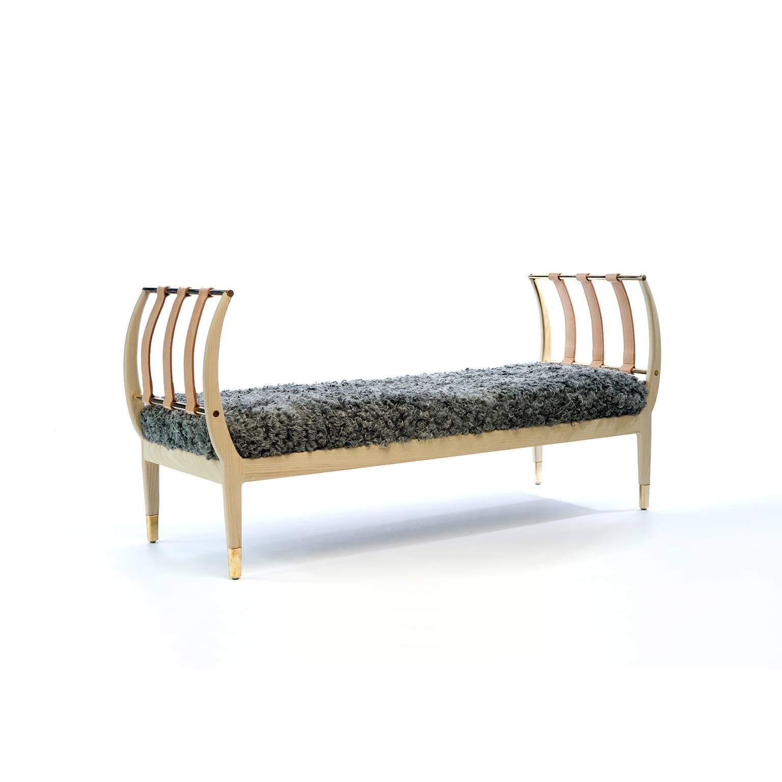 Resembling the rib of a whale, this American ashwood bench is complemented by brass rods and archs of vegetable tanned leather straps that are hand-stitched in waxed linen thread and accented with “x” type stitching. This bench can also be