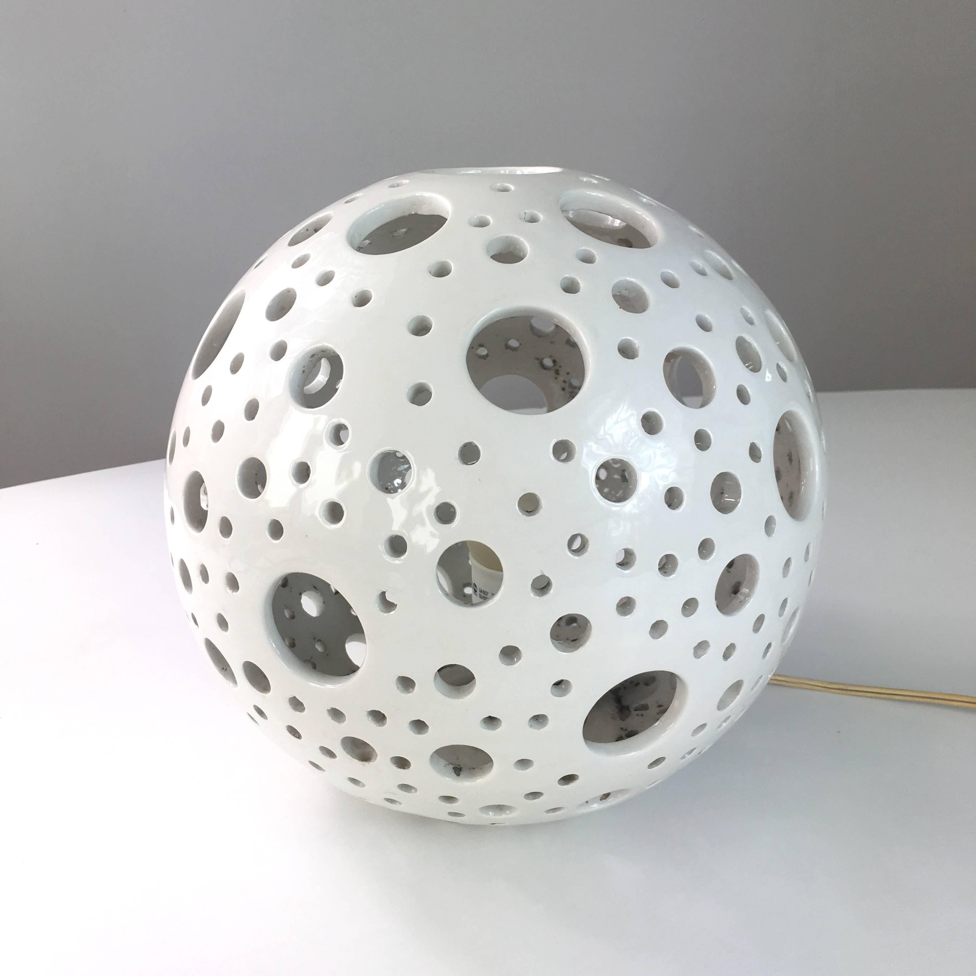 White ceramic lamp of 1970s time. Italian manufacture. Multiple circle gaps of different diameter are creating decorative lightning effect.