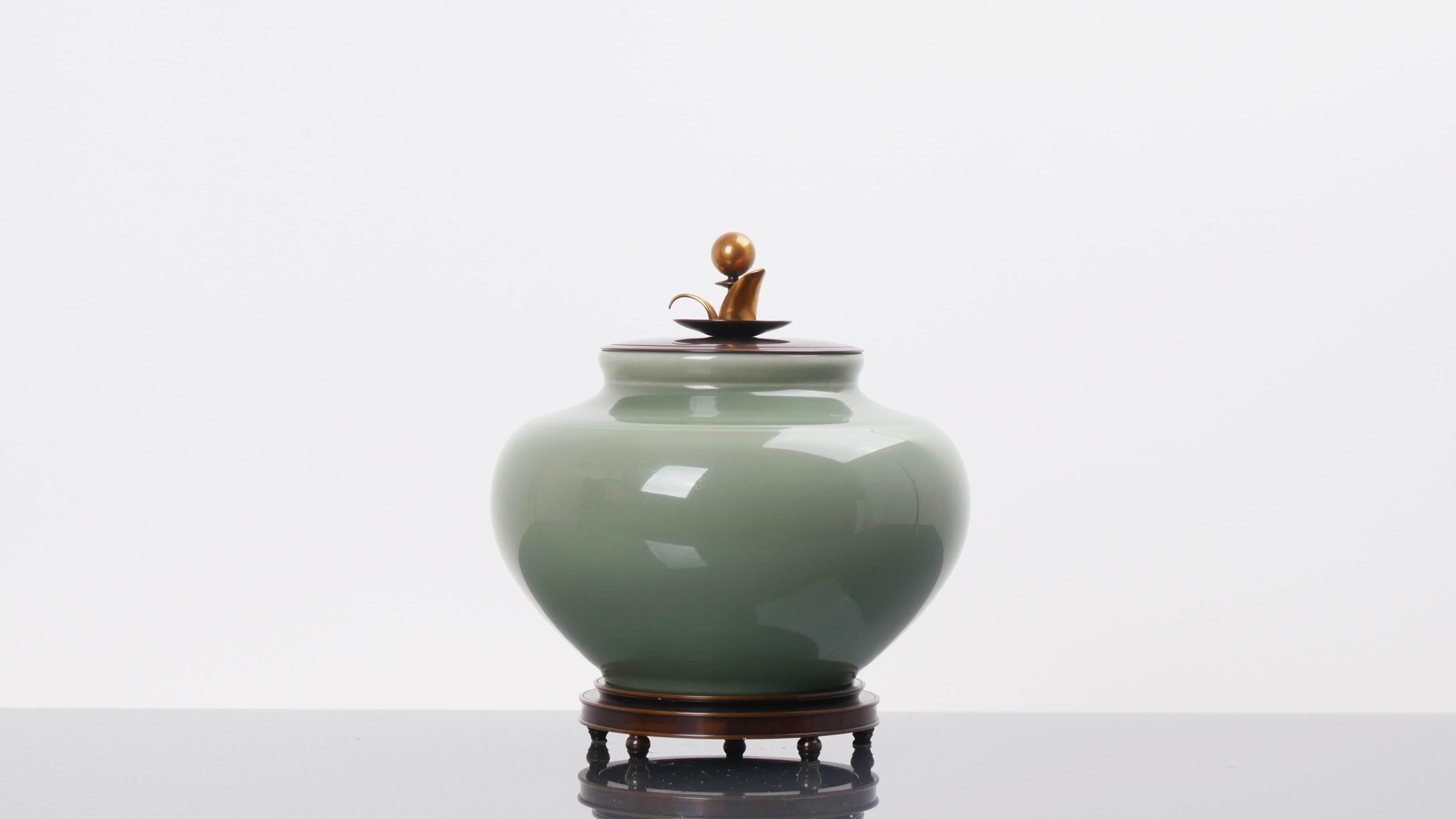 A large lidded jar in celadon glazed ceramic with the mark of the Royal Copenhagen on a bronze stand with a bronze lid signed "CA" for Carl Halier. The piece is in perfect conditions.