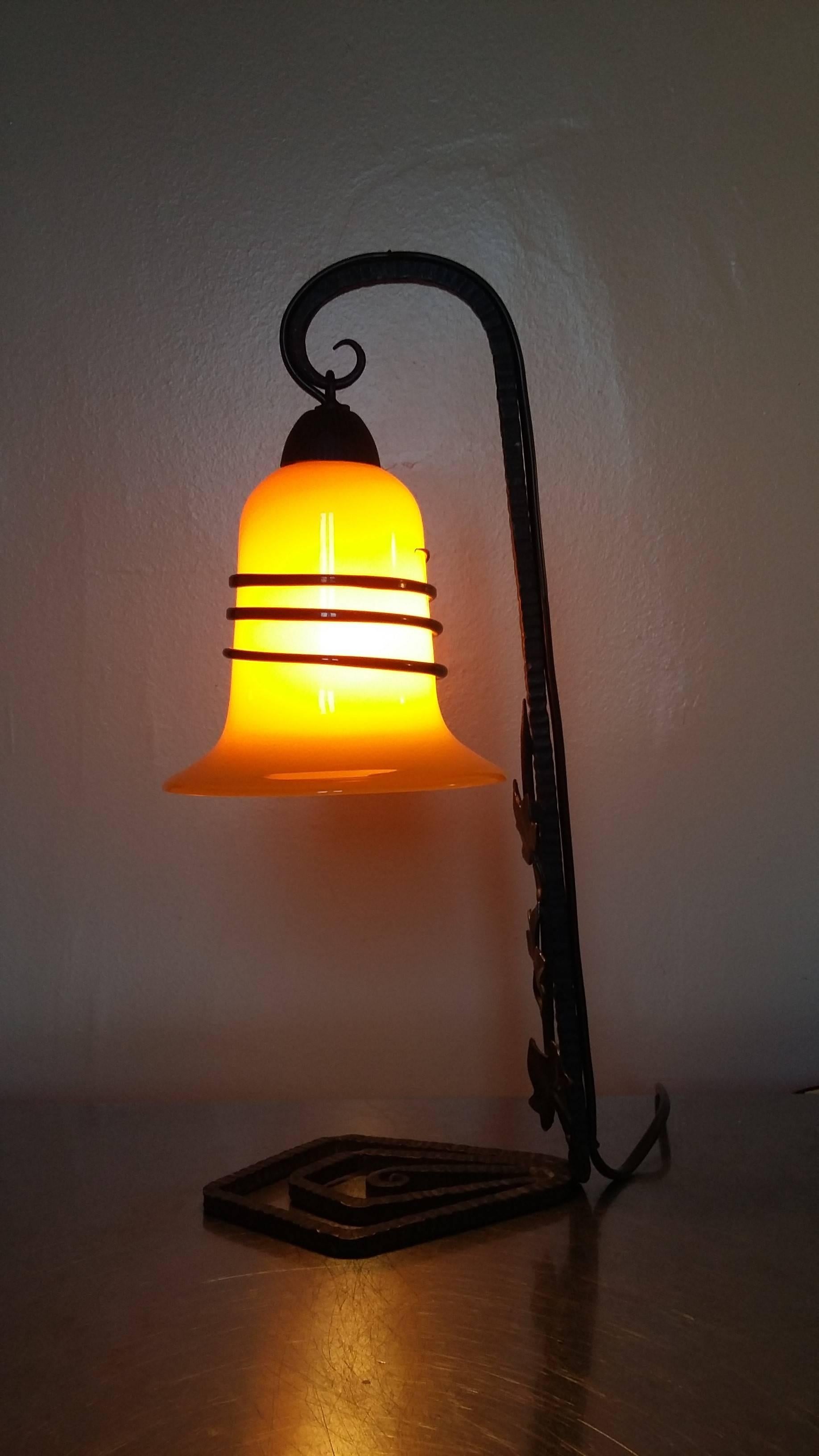 Art Deco table lamp in blackened and hammered wrought iron decorated with leaves and geometric lines, beautiful base and a tulip glass paste by Loetz Powolny in orange color decorated with a black serpent snake around.
In a very good general and