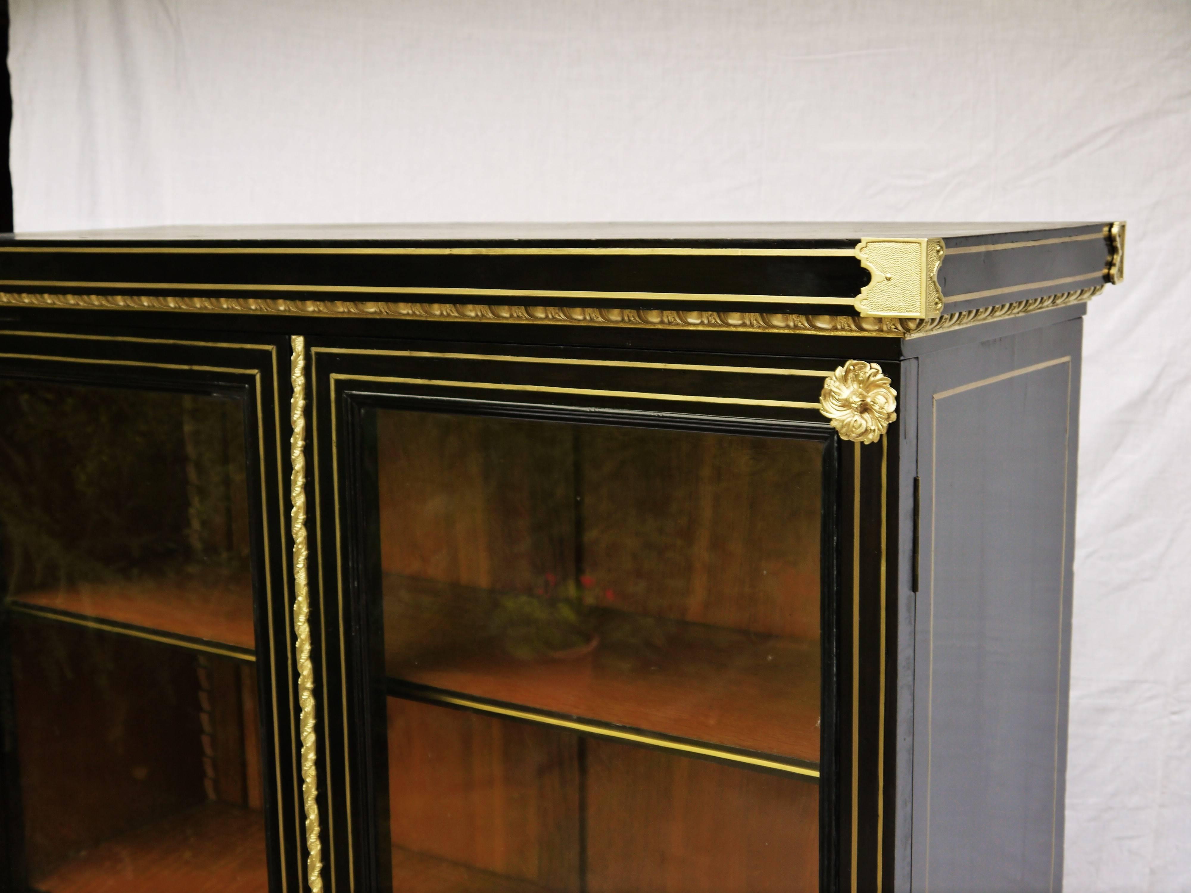 Elegant Bibliotheque, showcase, bookcase vitrine cabinet in Napoleon III style. Blackened wood decorated with Boule style marquetry with brass filets with two glass doors.
High quality gilt bronze ornamentations. The inside parts are in palisander