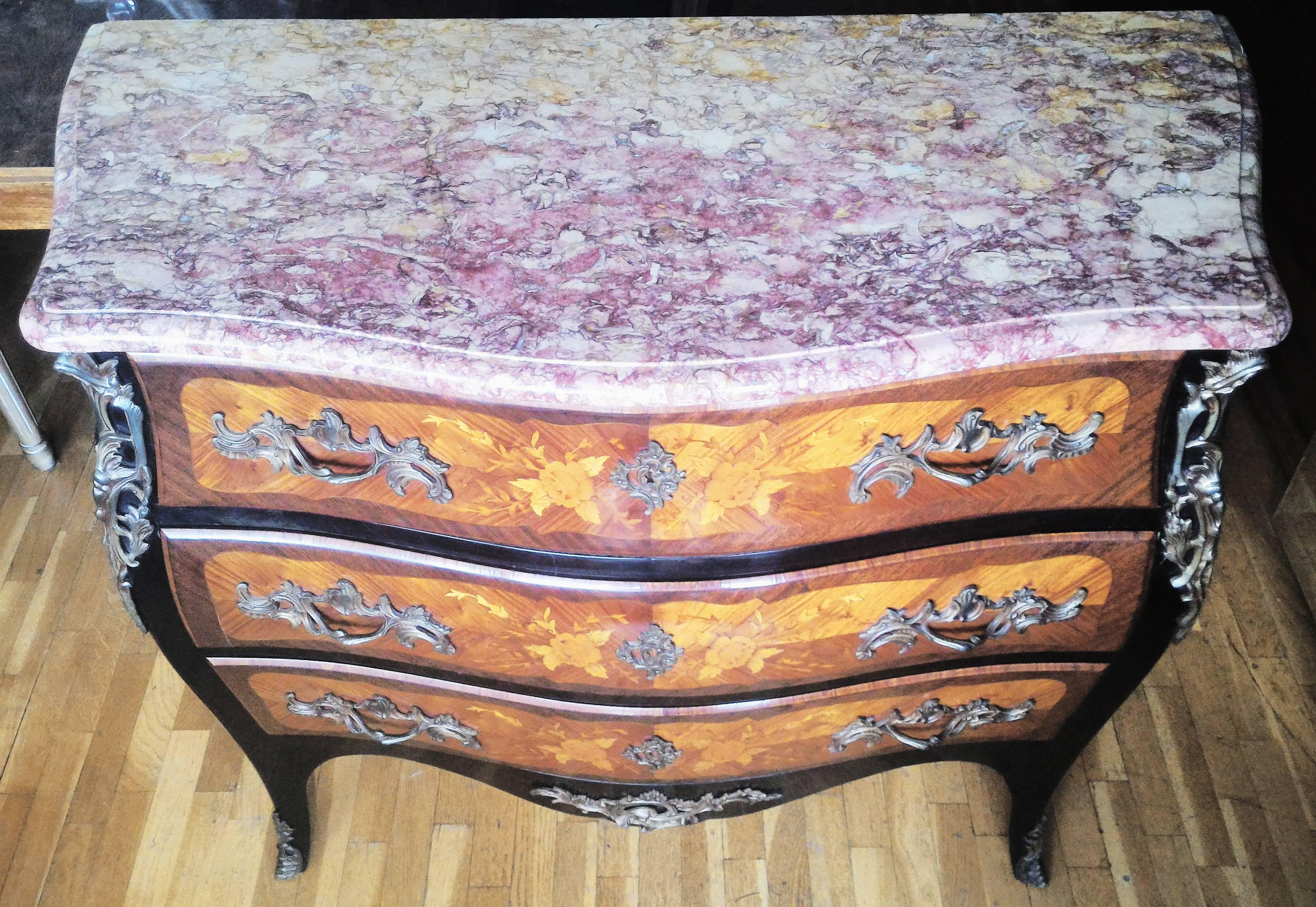 Elegant bedroom set in Louis XV style. Made in a beautiful inlay of several beautiful and different wood types marquetry floral composition. 
It has a sublime color mix of burgundy marble top , and bronze ornementations in gilded ormolu mounts that