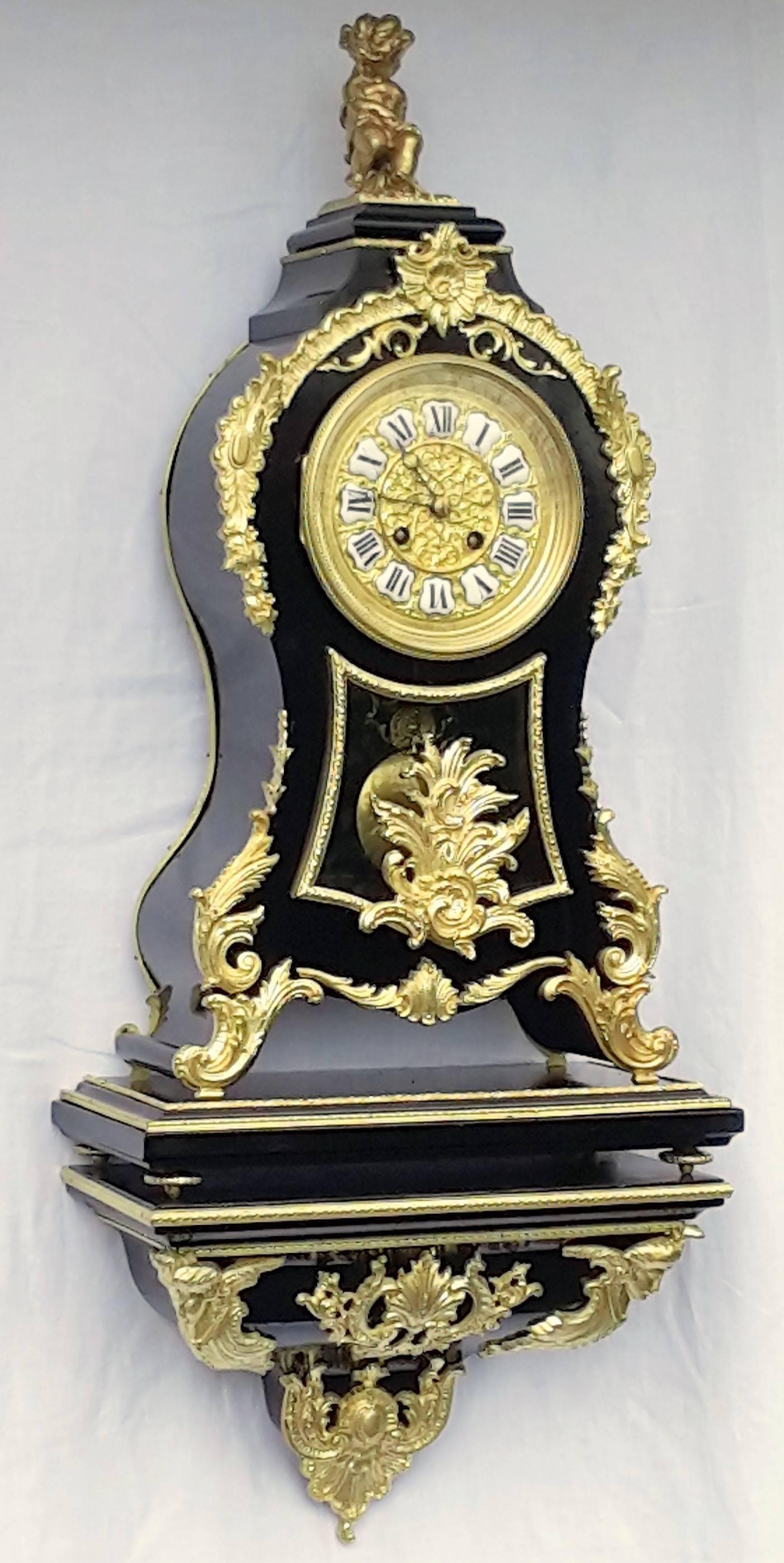 Unique Cartel wall clock and its elegant plinth, covered in black ebony wood, beautifully ornamented with many gilt bronze garnitures all over it. 


The clock (in three parts )works and the bell rings every half an hour and every hour, on a