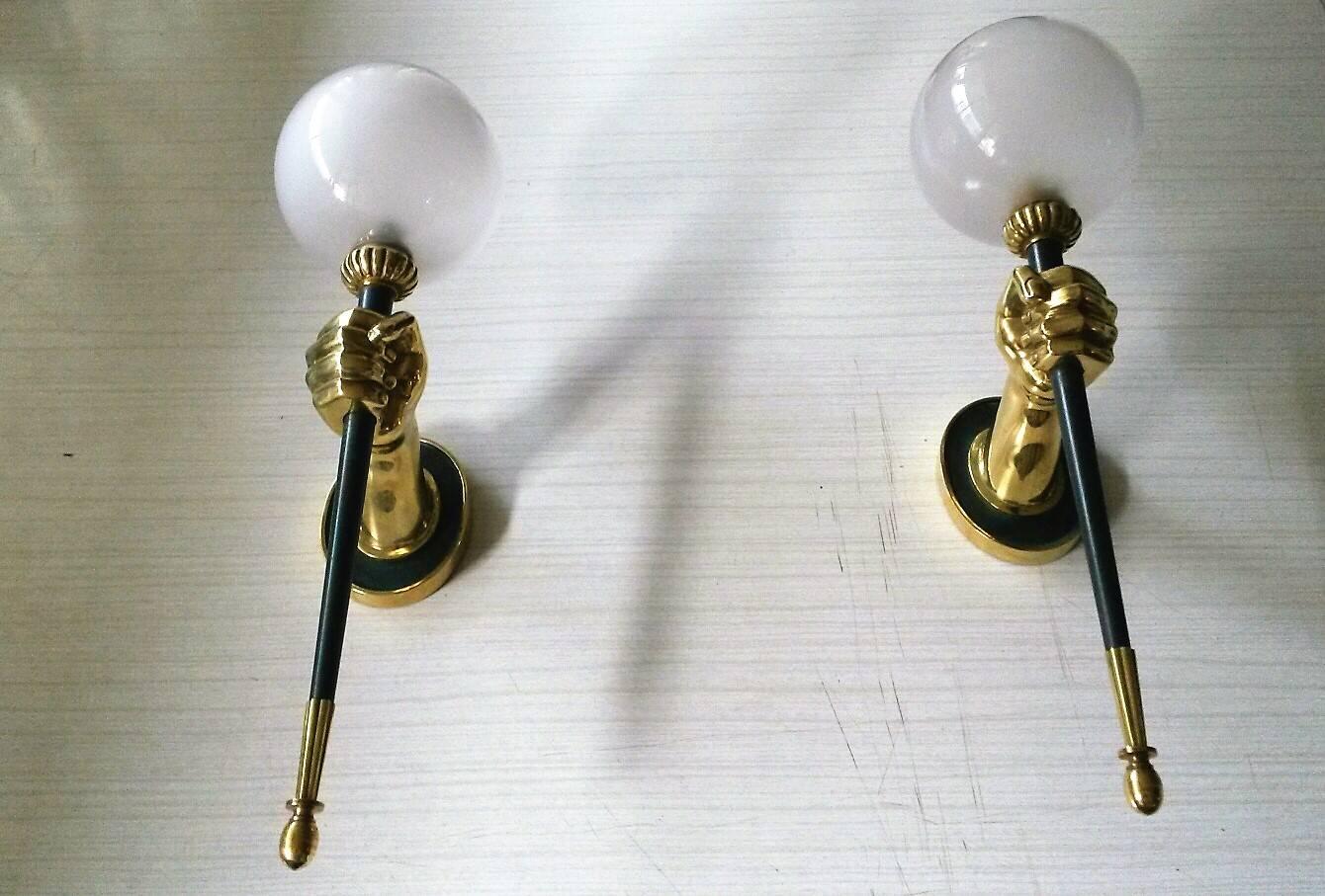 Pair of neoclassical gilt bronze sconces with dark green patina and sandblasted matte white globes. Representing golden hands holding a torch light.
By, Maison Jansen, France, circa 1950s.

In an excellent original condition, the dark green