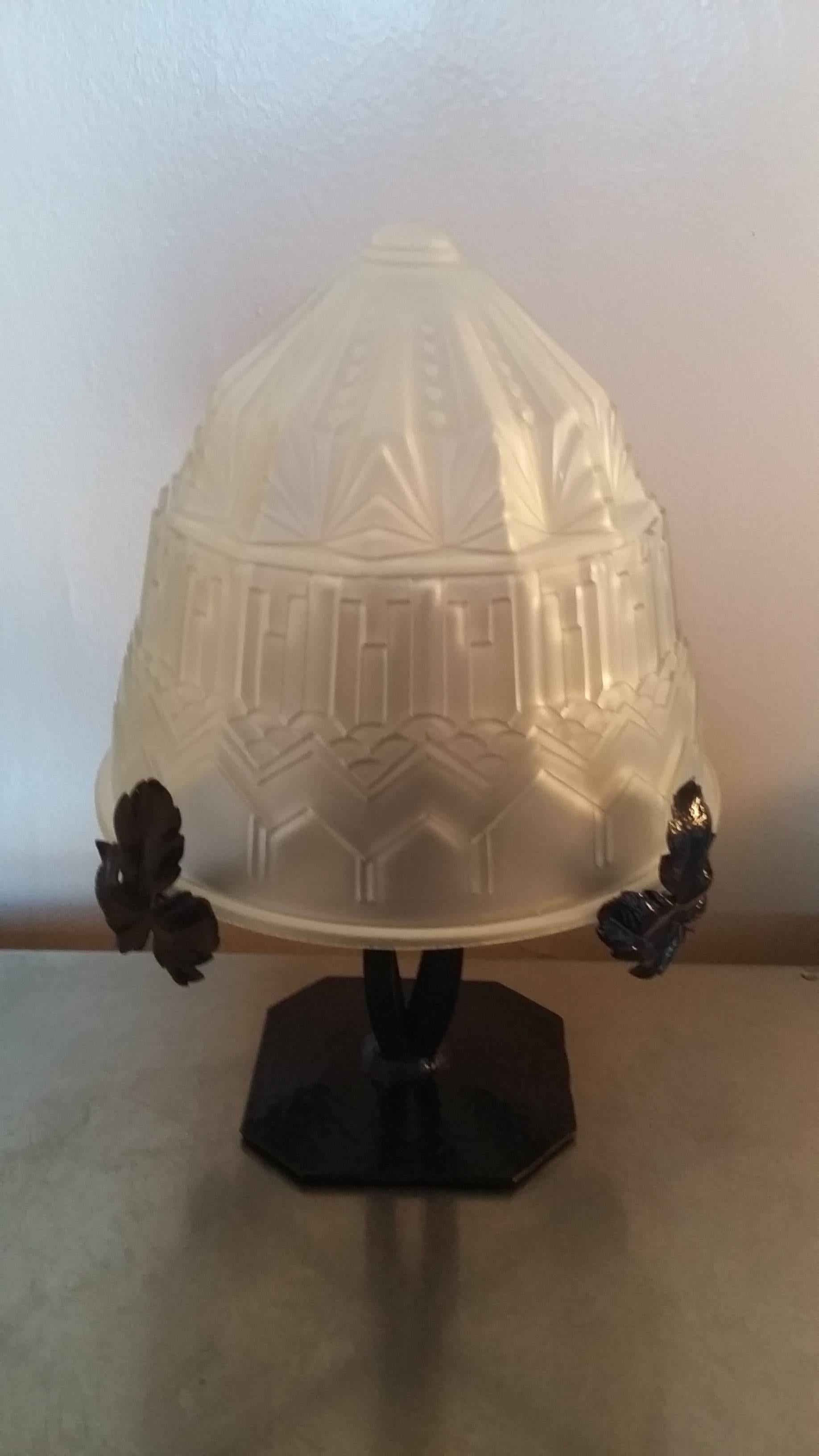 Art Deco table lamp in blackened and hammered wrought iron. A gorgeous molded glass paste with geometric lines seats on four arms decorated with vine leaves.
France, 1930s
In an excellent general condition, working perfectly, the electric part has