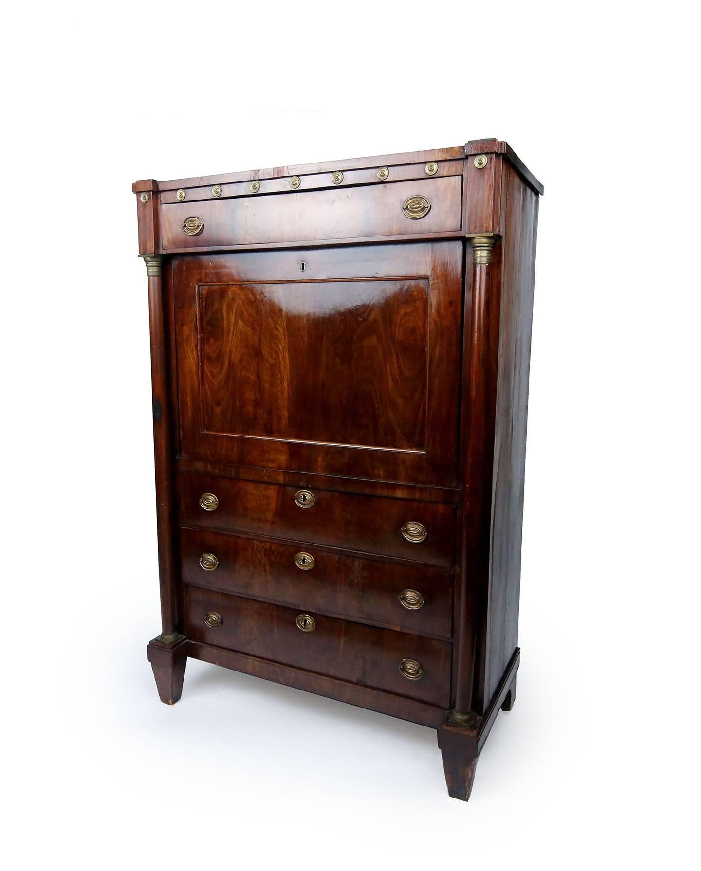 Architectural mahogany and oak fall-front secretary. The entablature drawer studded at the top by ornamental pressed brass with star design is supported by slim full round columns which rest on diminishing square bases. These columns have finely