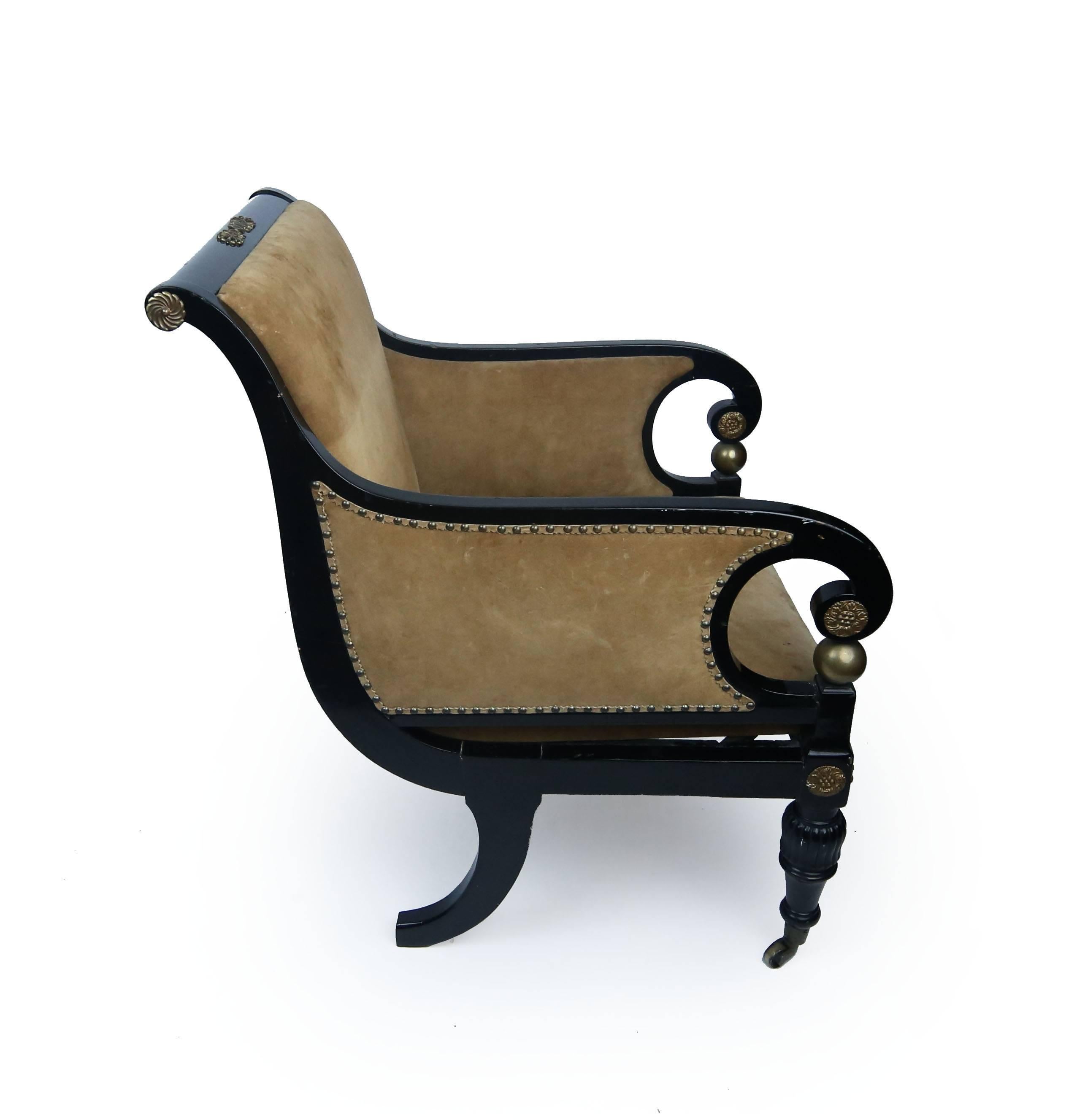 A Fine large classical club chair, black lacquered mahogany with sleigh back, spiral arms, brass decals, turned reeded front legs terminating in original castors, dramatic rear saber legs, upholstered in suede with brass tack nails. Made by Gillows