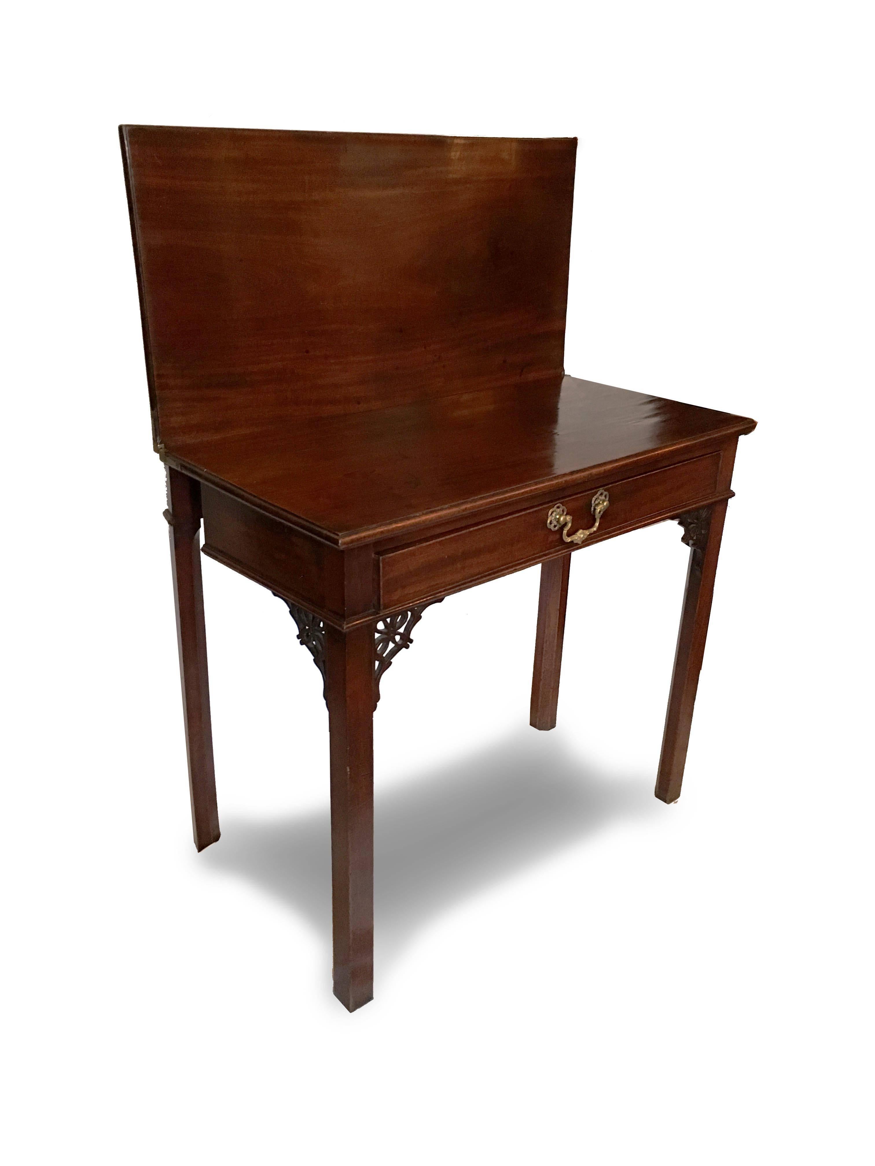 An English George III mahogany card or console table with rectangular flip topbearing a molded edge. The top is supported by a frieze drawer with period brass pull. Presumed original pierced brackets join the case to the square moulded legs. A gate