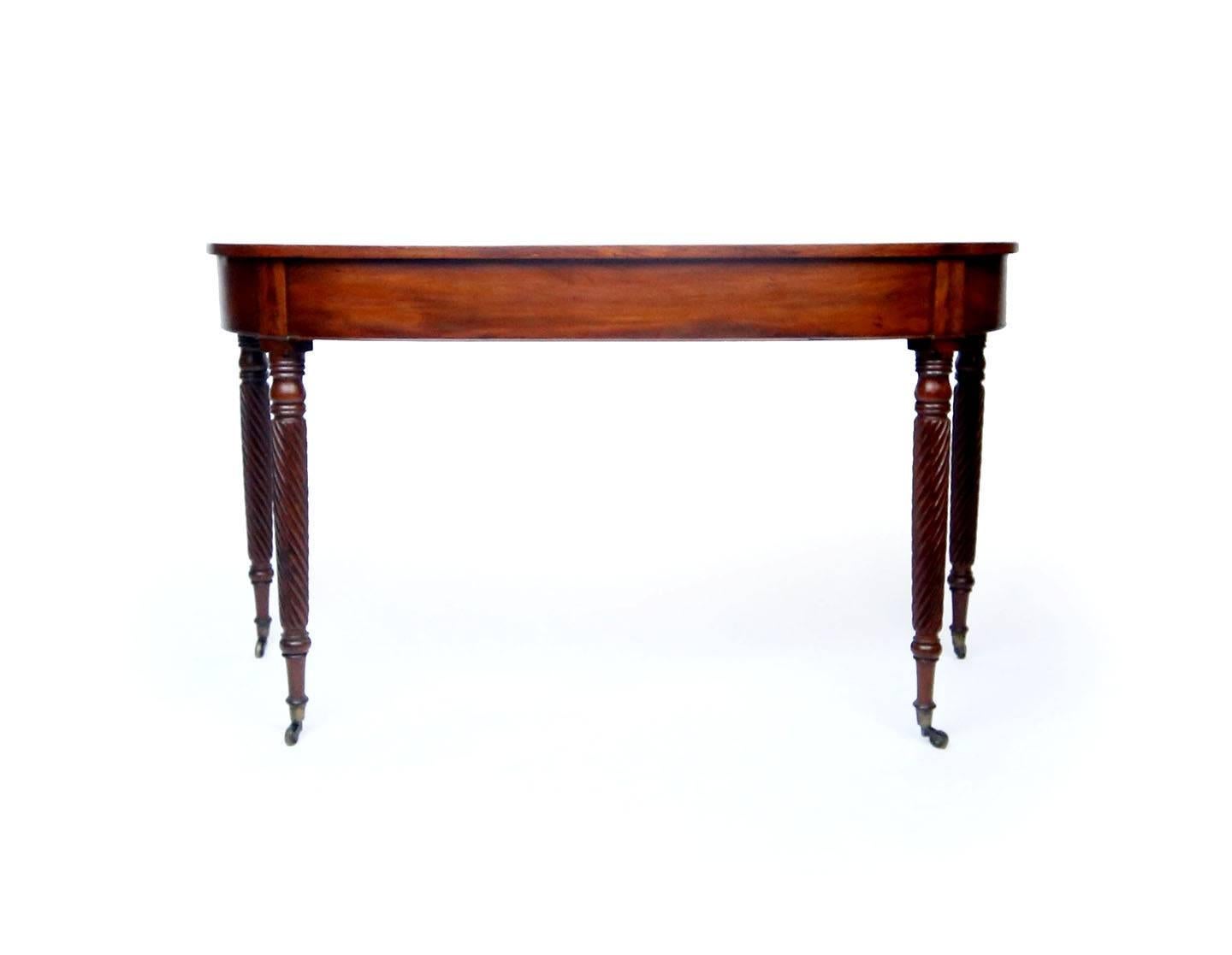 Beautiful early 19th century light mahogany table. Originally a set to form a banquet table, this table makes an excellent console or small sofa table. Four tapering legs carved with signature Allison spirals end in original castors. Workshop of
