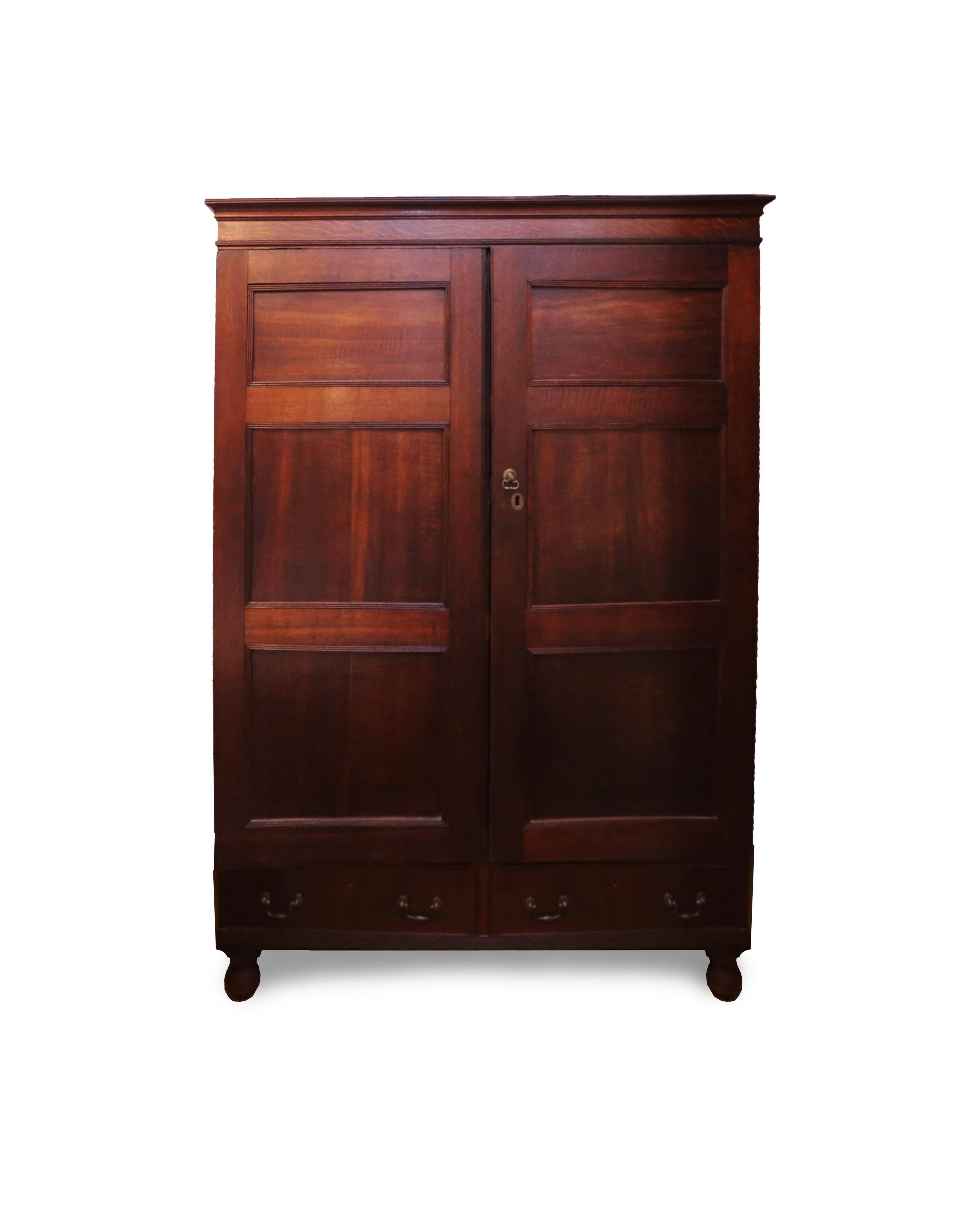 A stunning armoire with clean simple lines and masculine, handsome proportions. The coloring is particularly fine with a deep amber hue. The case sits on bun feet with concealed castors. A simple cornice crowns the top with Fine incised beaded edges