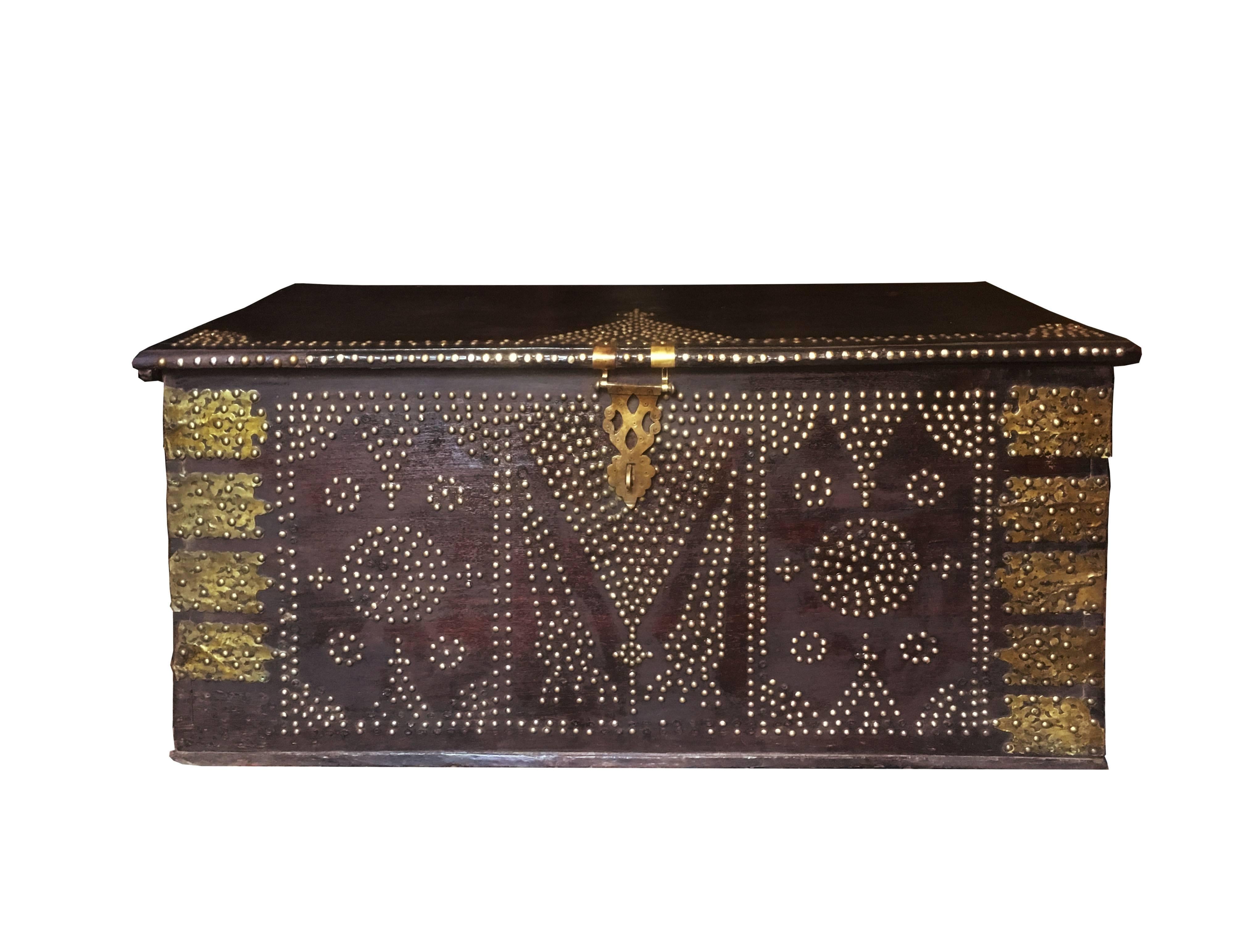 A stunning rare 19th century Zanzibar or Bombay chest composed of six thick slabs of teak wood. The exterior of the trunk is outfitted with brass sheets and studs in geometric patterns, particularly pyramidal shapes mounted by crosses, representing
