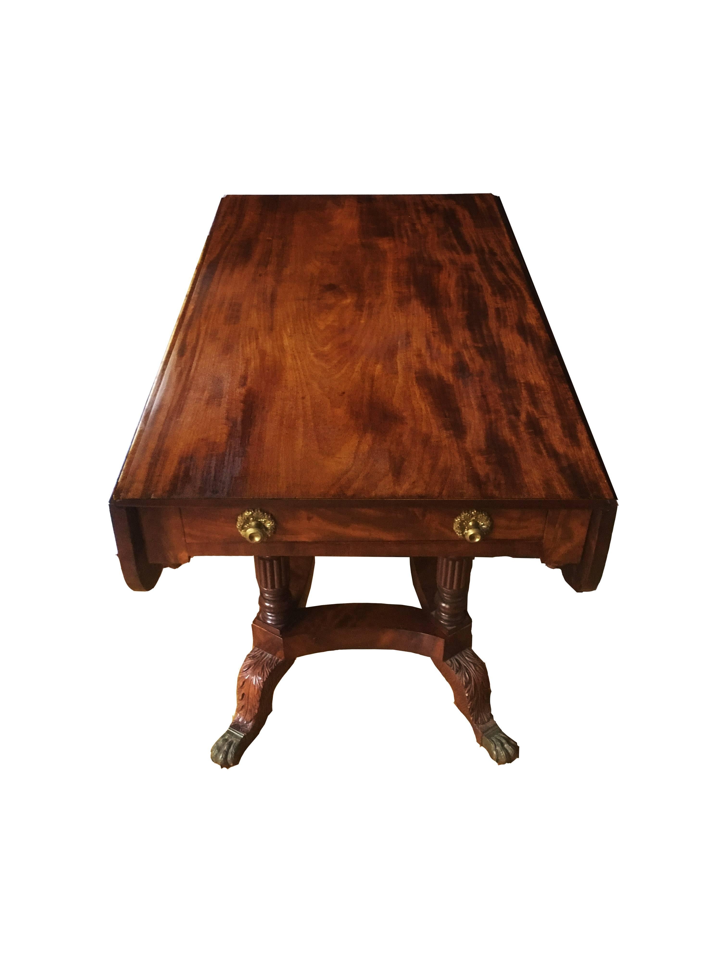 An exceptional New York breakfast table composed of the finest rib boned mahogany and masterful carving. The Pembroke table has one drawer with original brass ormolu pulls and a matching flare drawer opposite. The scalloped edged top is supported by