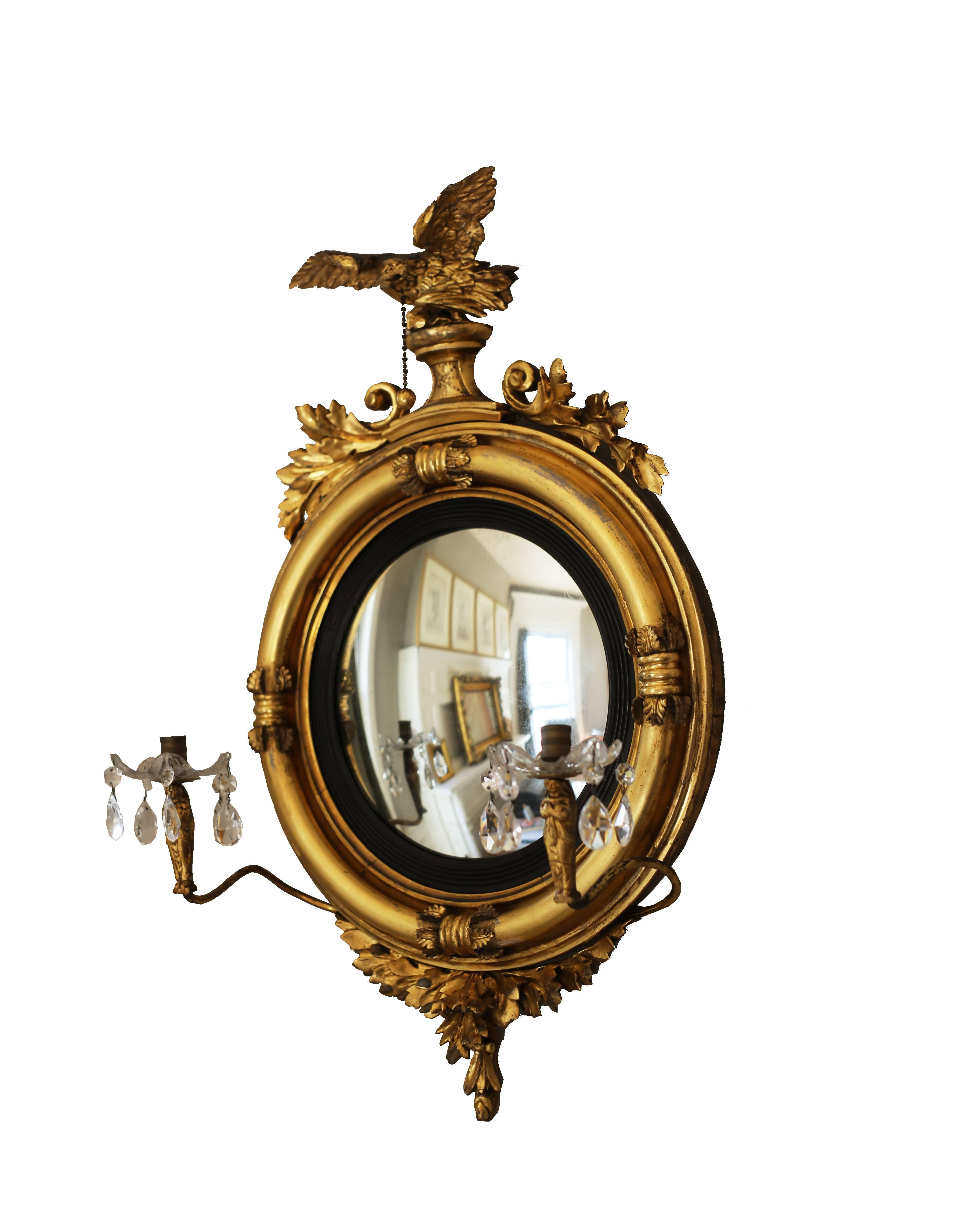 A rare diminutive girandole mirror, circa 1815, in extraordinary original condition and possibly American. The looking glass features a bold acanthus apron, ebonized reeded filet, surmounted by an eagle bearing a ball and chain from its beak.