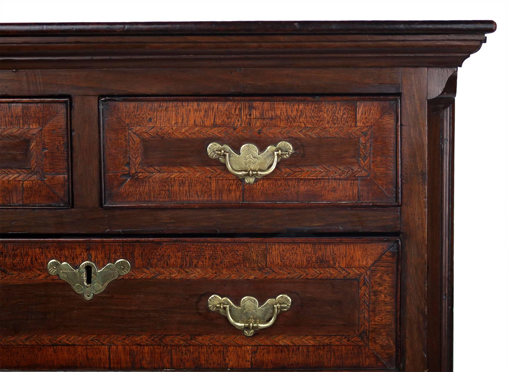 A rare highboy of diminutive proportions in walnut and mahogany with fine marquetry, feather banding, and cockbeading. The molded cornice is set on the upper case with canted and molded corners, containing five drawers. The lower case has three