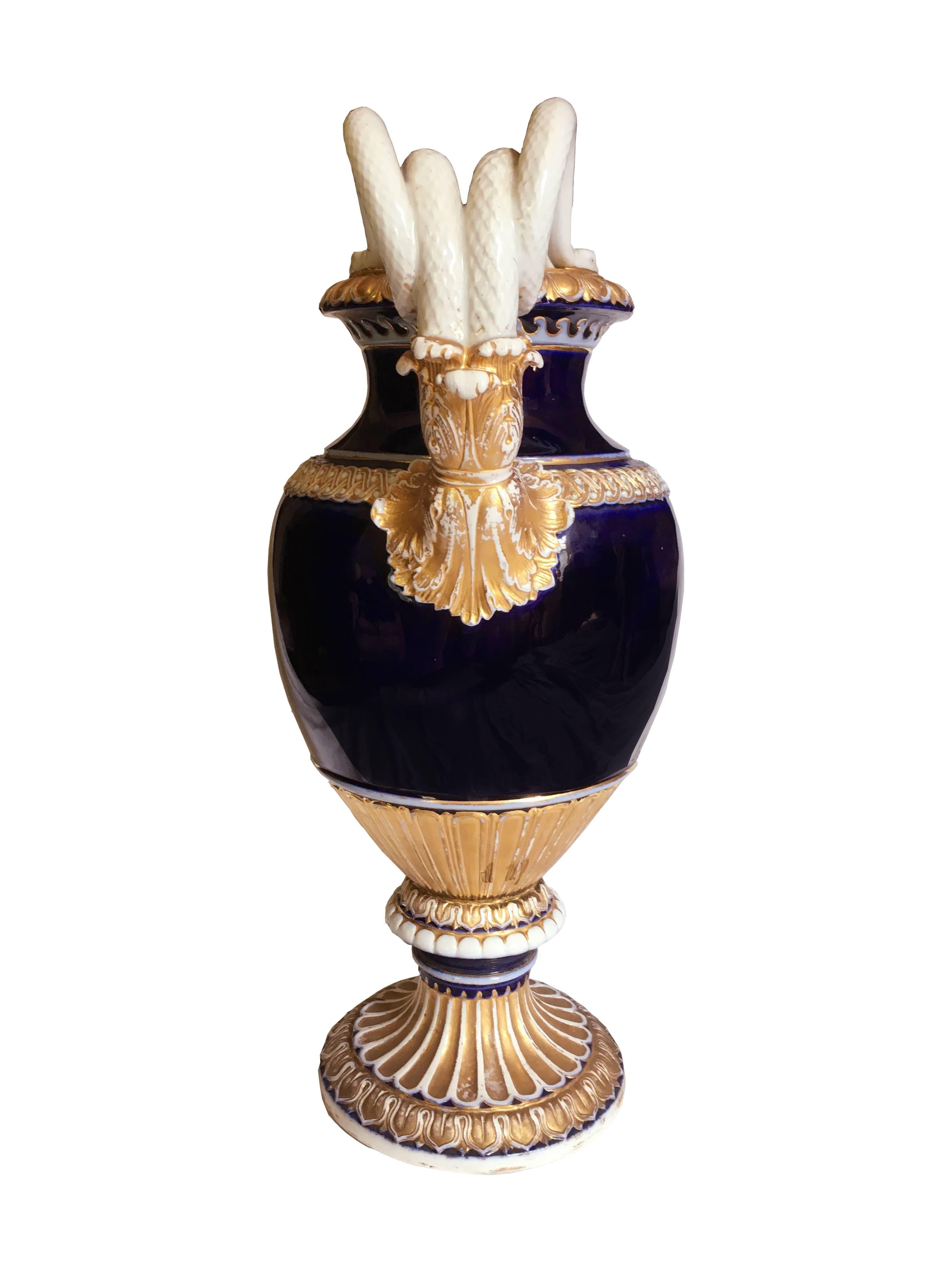 Vase en porcelaine de Meissen, cette belle pièce présente un corps bleu profond avec des poignées serpentées à terminaison acanthe. La base est godronnée et cannelée avec de fins détails classiques de langue de mouton et d'œuf et de fléchette,