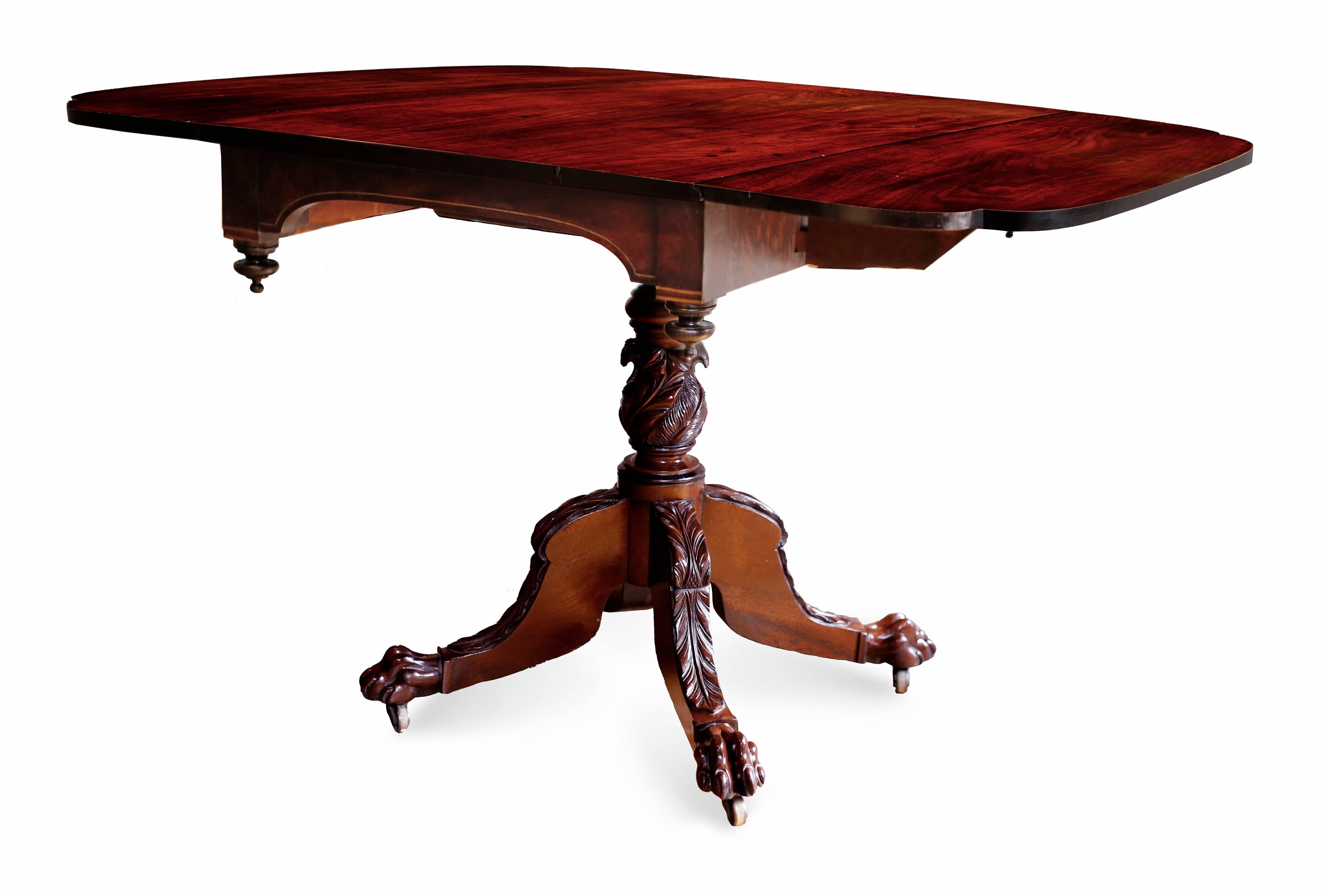 A fine Federal breakfast table in black walnut with a rectangular top and drop-leaves, the corners of which end in cyma curves, with inverted wooden finials. The table skirt also features brass inlay, supported by a turned acanthus and plume carved