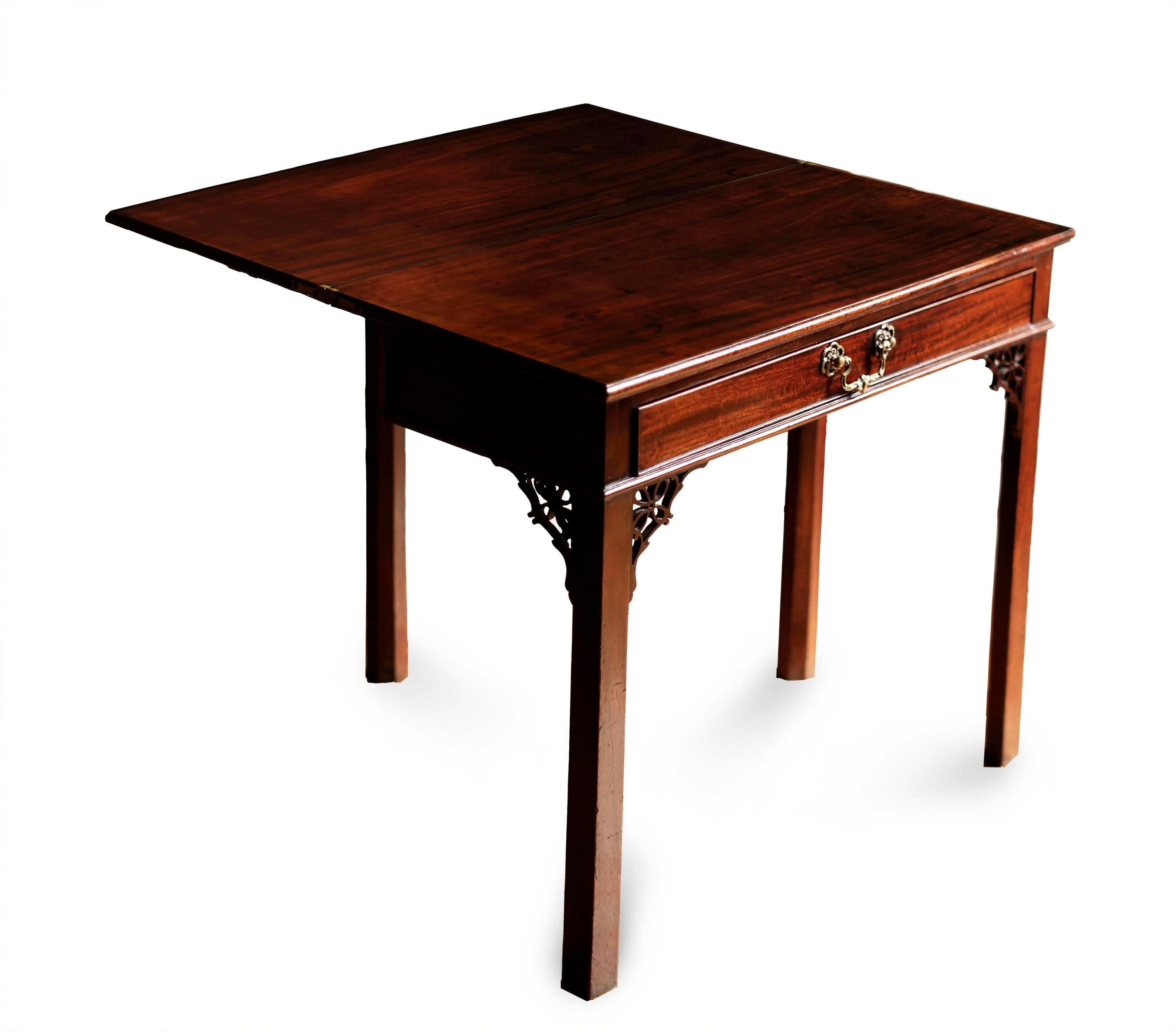 An English George III mahogany card or console table with rectangular flip-top bearing a molded edge. The top is supported by a frieze drawer with period brass pull. Presumed original pierced brackets join the case to the square moulded legs. A gate