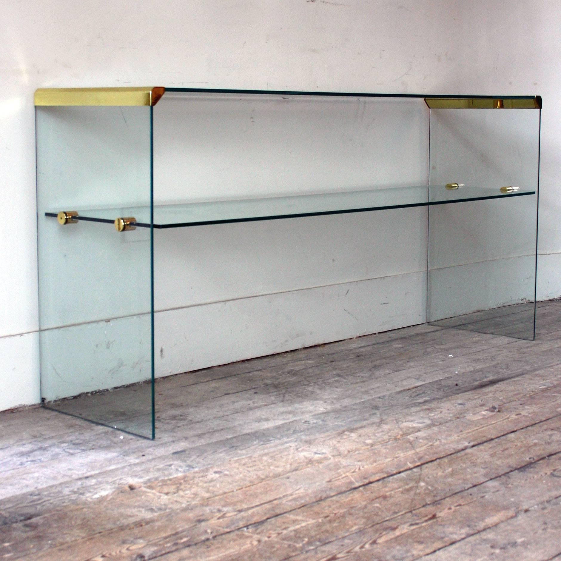 This large Italian glass console table from Pierangeli Gallotti was produced in the 1980s by Gallotti & Radice, the console has thick tempered transparent glass and has stainless steel gold colored edges contrasting beautifully against the