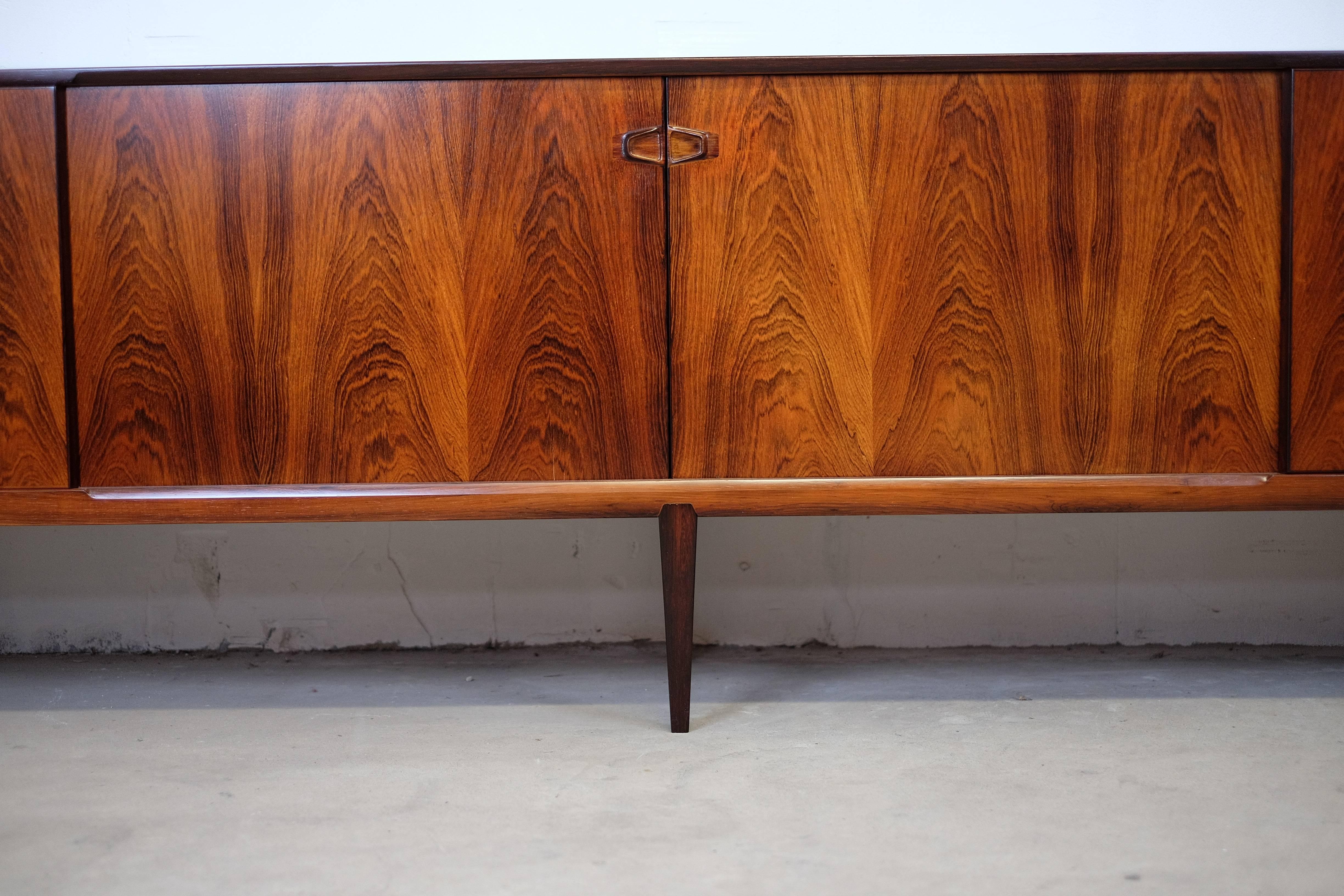 Look at this stunning long sideboard by Rosengren Hansen for Brande Møbler.
The rosewood is incredible beautiful!

This piece is allmost in mint condition. Inside complete, with all drawers. Four beautiful sliding doors with some amazing grips.