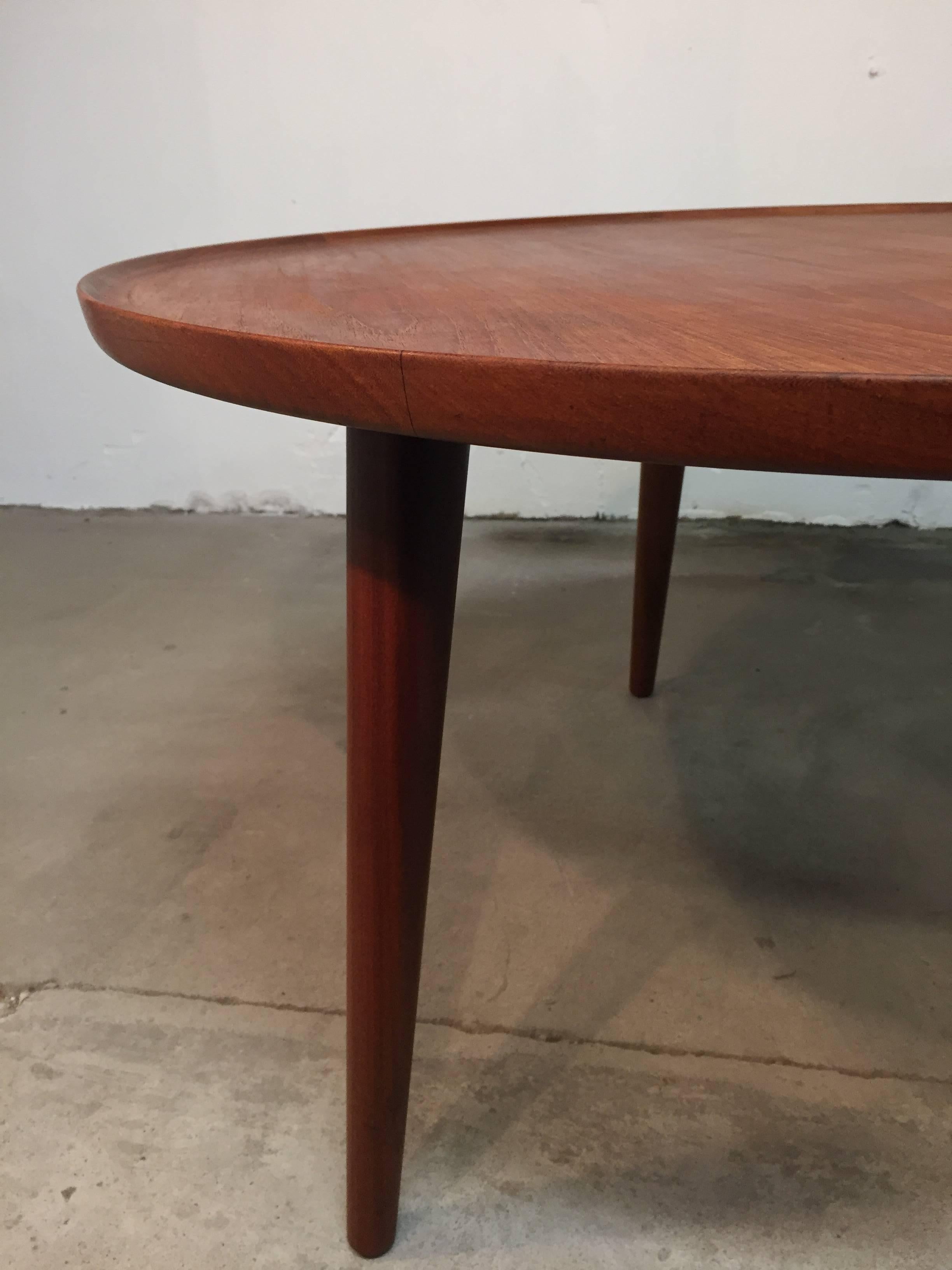 This beautiful circular coffee table in teak, has some amazing details, with angled legs and raised edge. There is no stamp under the table but I am almost sure that it is designed by Anton Kildeberg.

The table are in good condition but has some