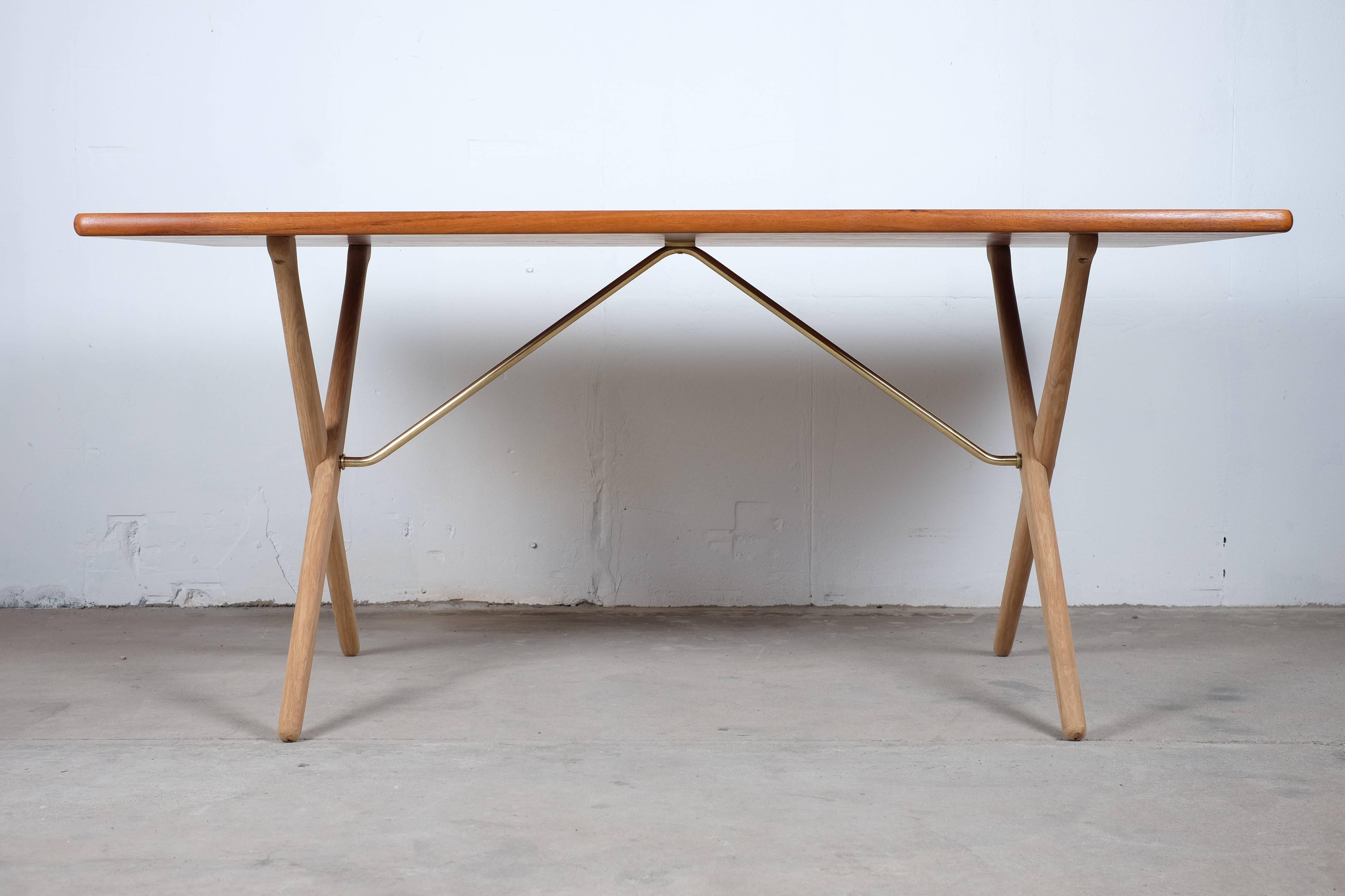 Rare dining table with cross legs - model AT-303 designed by Hans J. Wegner. Produced by Andreas Tuck in Denmark. 

The table legs are made of solid oak and supported by beautiful brass brackets. The tabletop is teak.

The table has been to an