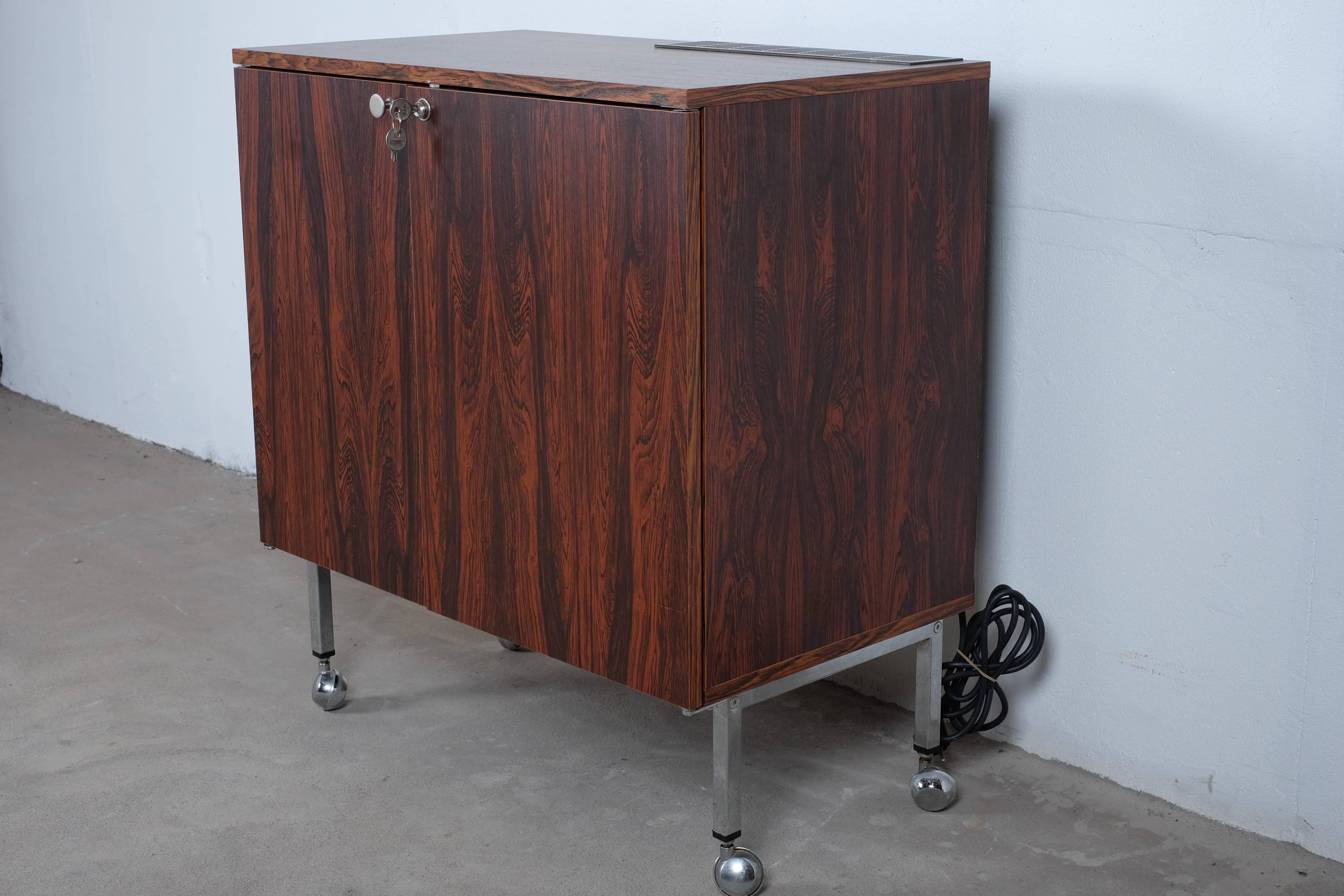 Desirable rosewood bar cabinet in rosewood with fridge (Electrolux) and a small freezer for ice cubes. Light turns on when the door is opened. Locking cabinet opens to reveal storage for all necessary bar accoutrements

I haven’t been able to find