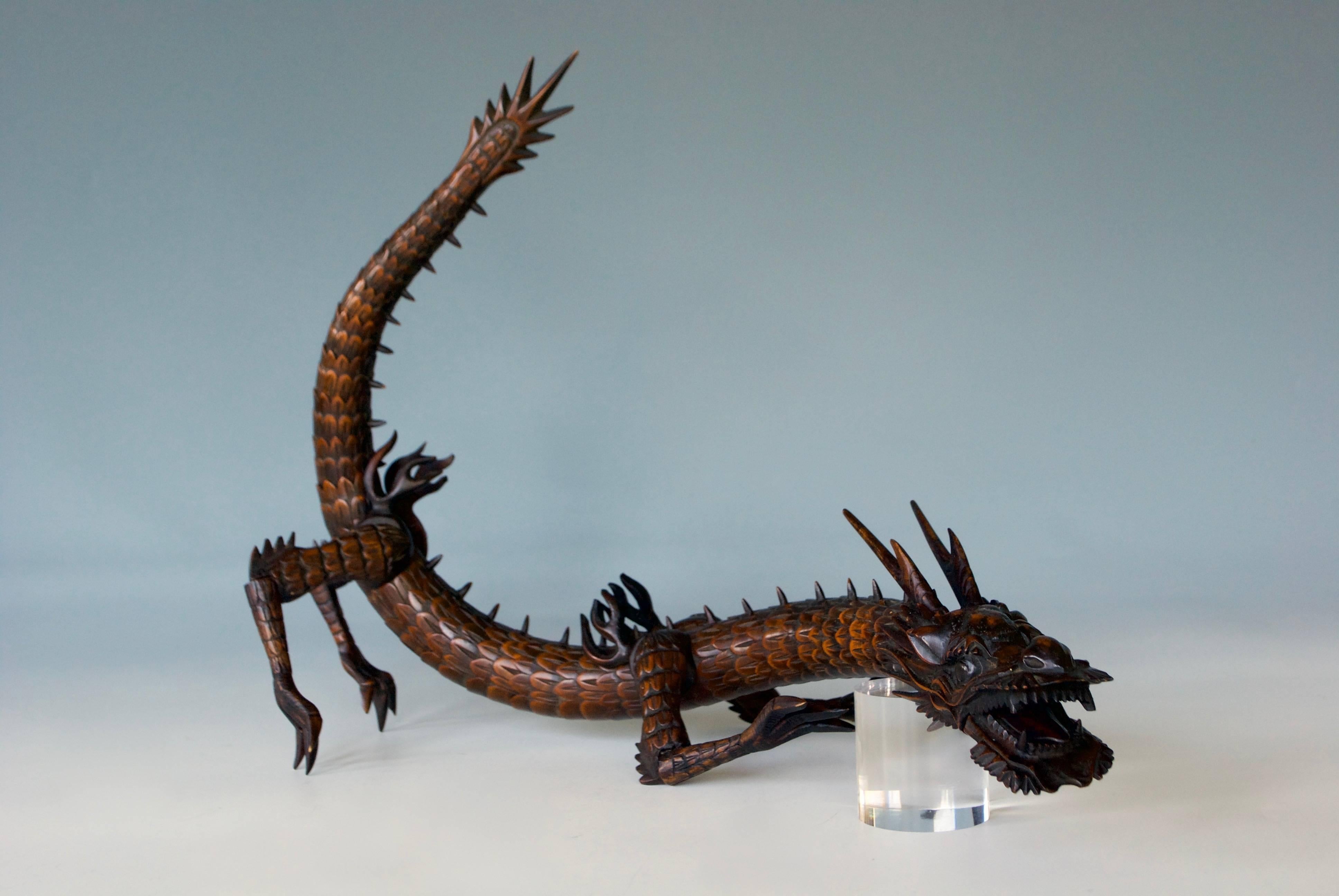 A Japanese fully articulated boxwood okimono of a dragon, the body intricately carved with scales and dorsal spines and a well-carved head, legs and claws; its jaw movable with a protruding tongue, the eyes inlaid in Horn.