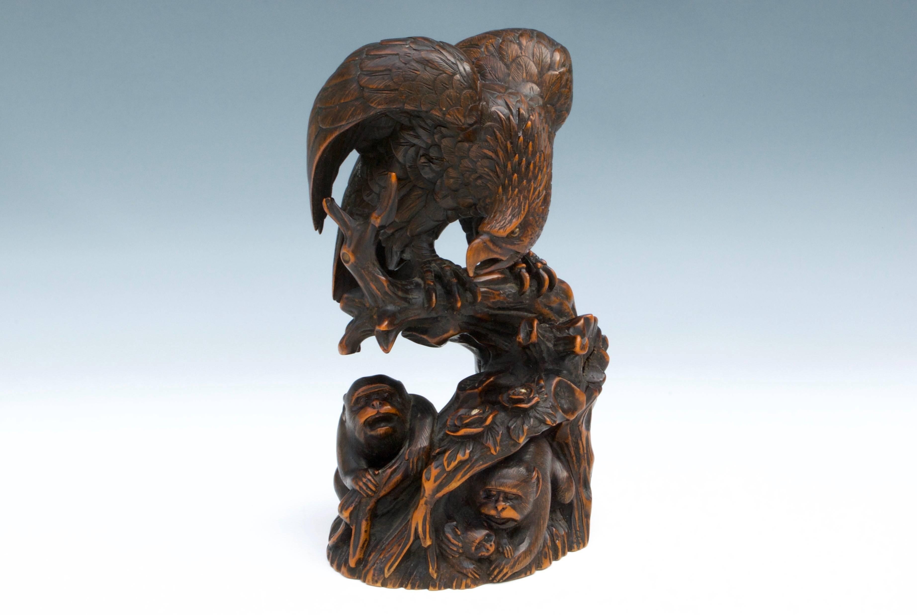 An impressive boxwood carved okimono of an eagle with blonde and black horn eyes watching with monkey at bottom. Signed Mokuto under the base.