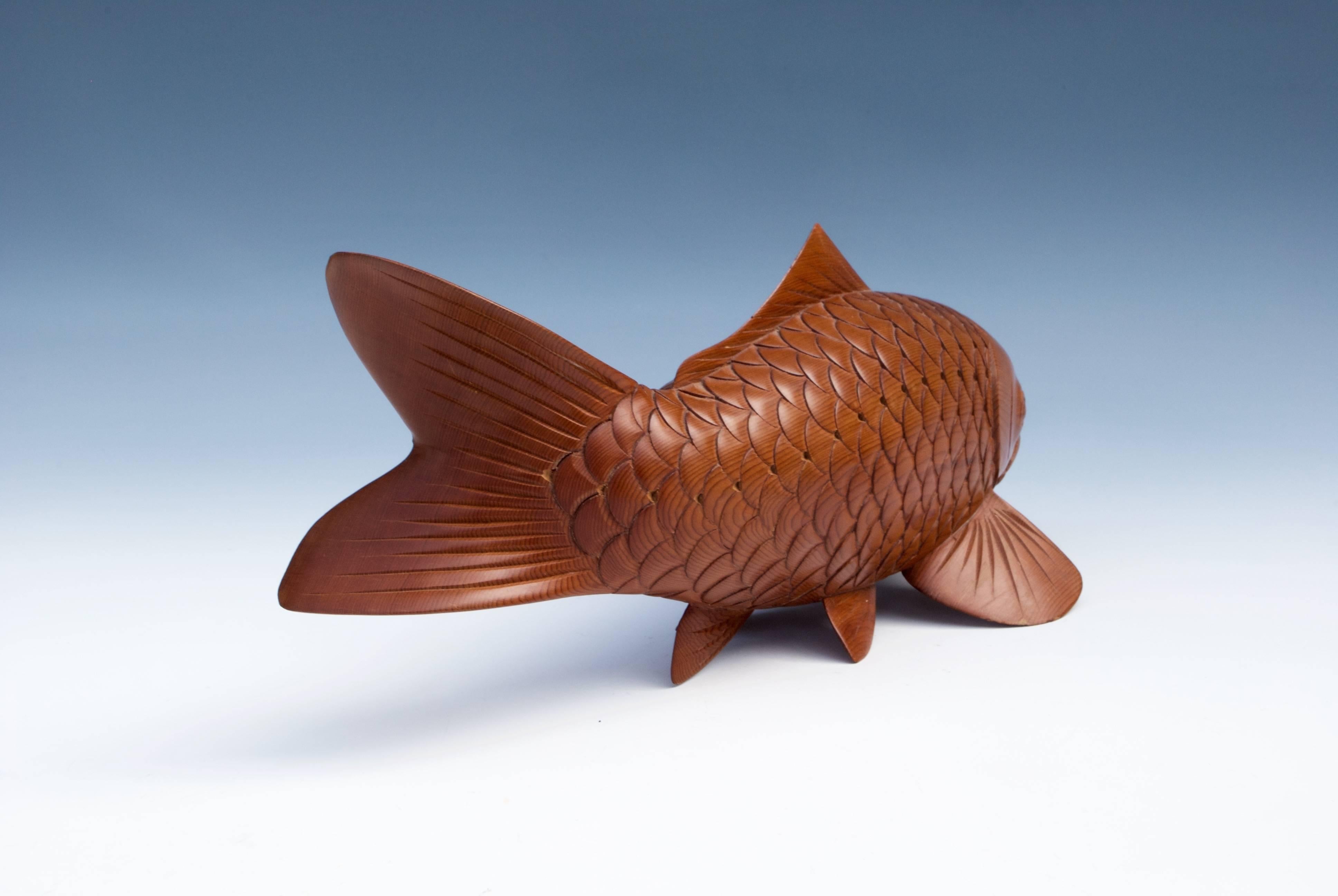 A Japanese senoki wood okimono of a koi carp finely carved with its body slightly curved to the left. Signed under the fin.