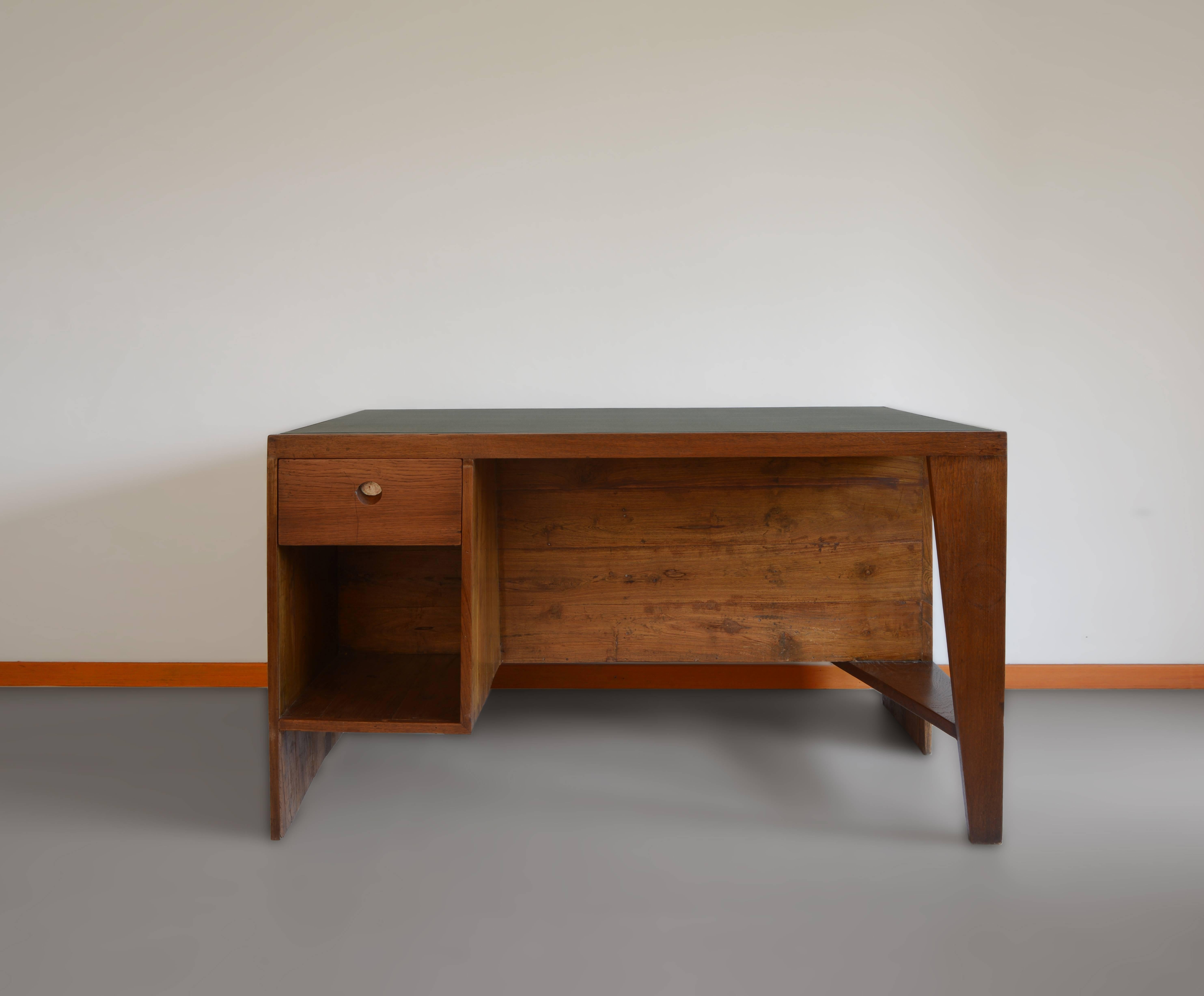 Office desk, 1957-1958. Rectangular top covered in black leather on a frame, affixed on one side by a panel forming a left side leg with a box section including a drawer and compartment and on the other side, a profiled leg with a flat triangular