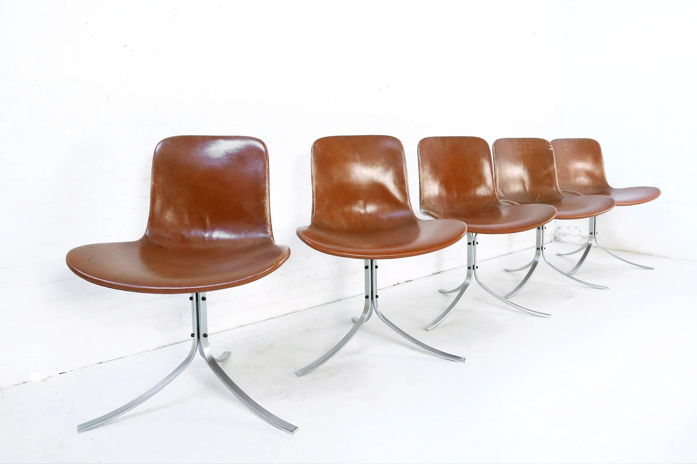 This iconic and first edition set of five PK-9 chairs was designed by Poul Kjaerholm and produced by E. Kold Christensen in the 1960s. The chairs feature their original patinated cognac leather upholstery. There is a maker's mark on the three curved