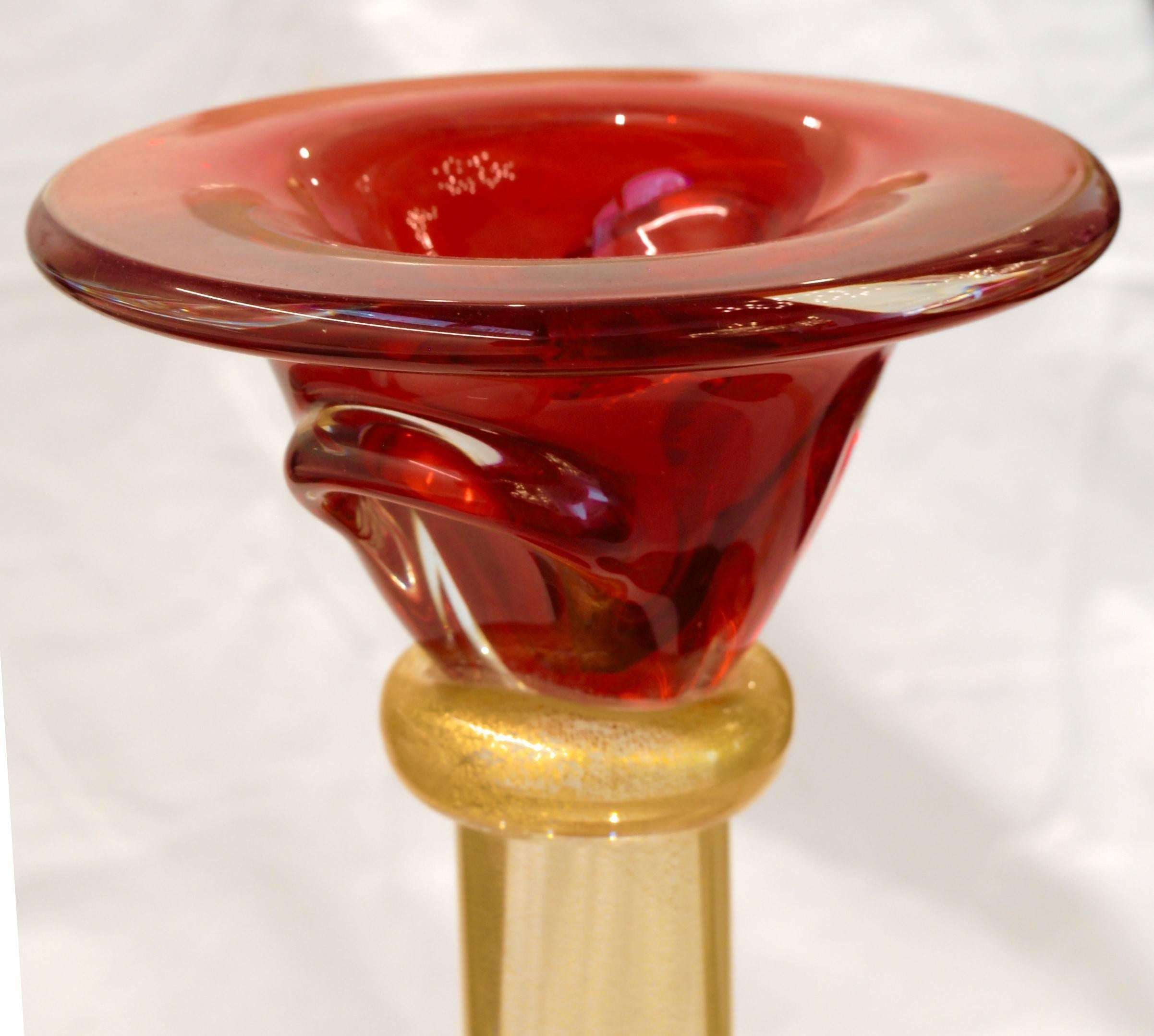 A pair of sumptuous candlesticks. Central stem is a cylindrical rod in gold leaf, base and top in red clear glass and connecting collars in gold leaf. 
Tall, heavy and awesome, on a console or a dining table celebration set up.

Romano Dona,