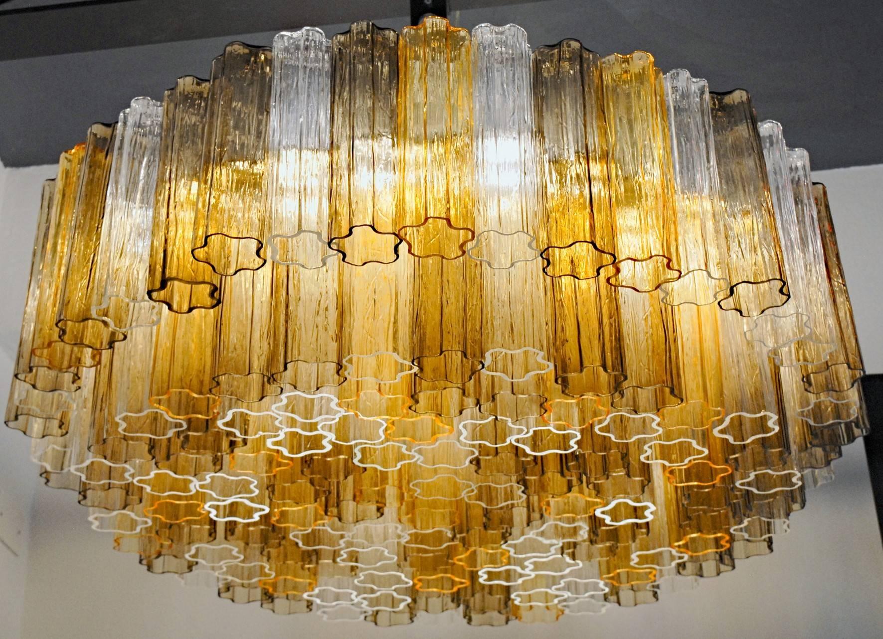 This chandelier was designed by Toni Zuccher for Venini. Rare color combination with amber, clear and taupe grey. The cut at the bottom of each element is highlighted when lit, see pictures. There are more than 120 glass Murano glass blown