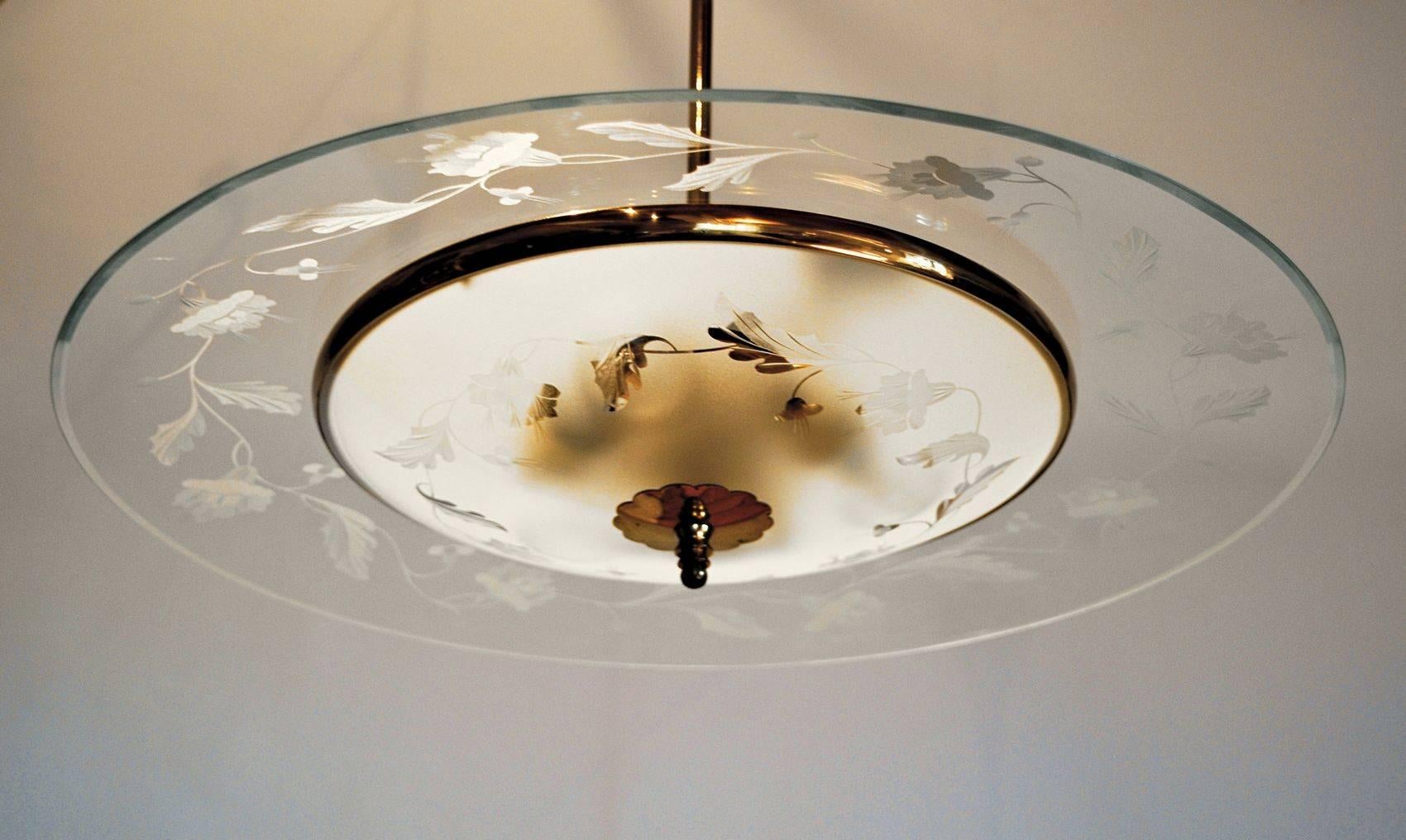A beautiful chandelier from Fontana Arte. The decoration has hibiscus flowers and it's hand chiselled not etched. The disc covering the bulbs is etched on the background but even here the details are hand chiseled. Hardware is in very good