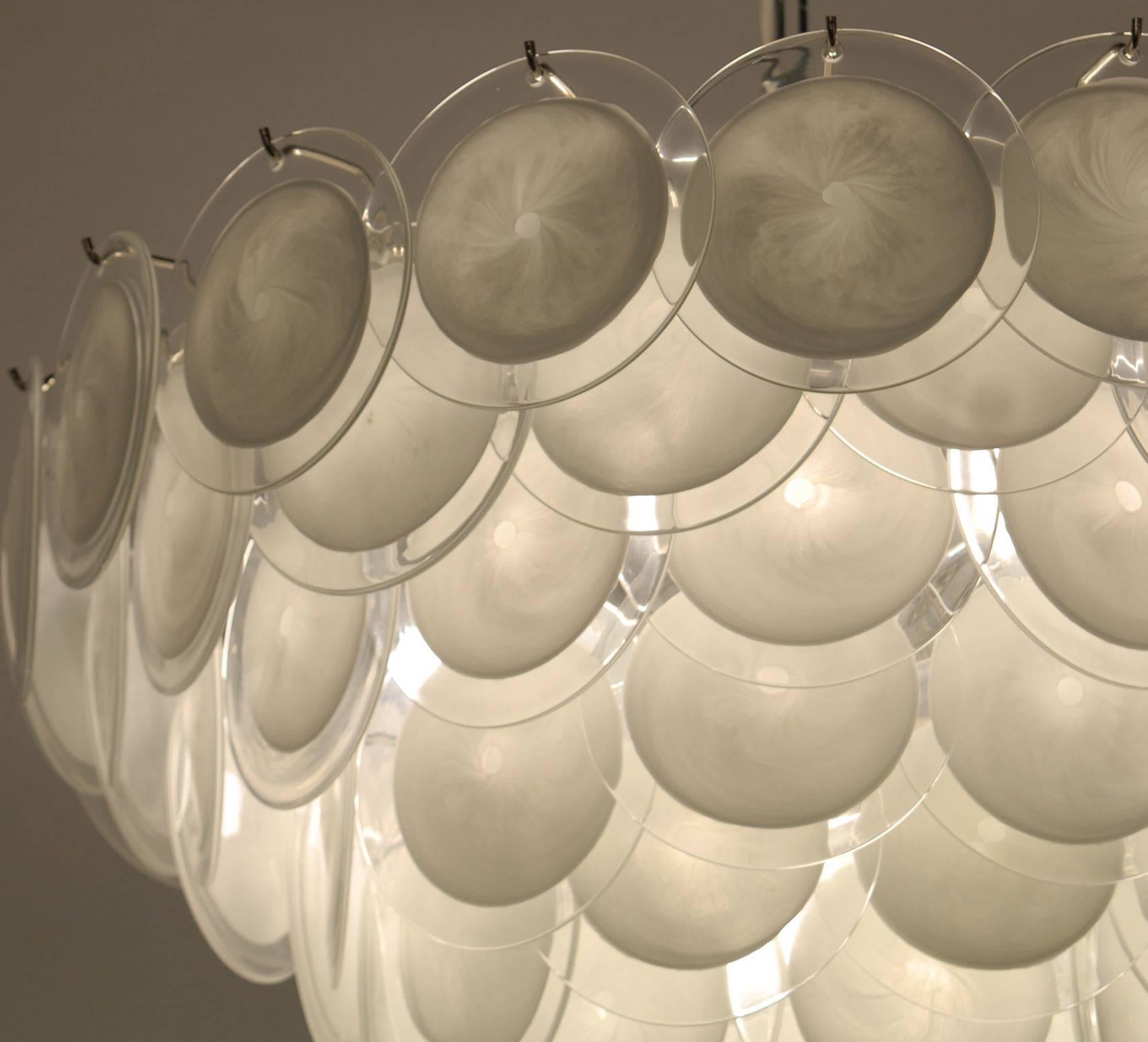 This beautiful chandelier carries over 80 discs made with the rullati technique. The same technique is used to make Renaissance windows. White glass Sommerso with clear glass, and then hand opened and flattened. Pontil mark still visible to assess