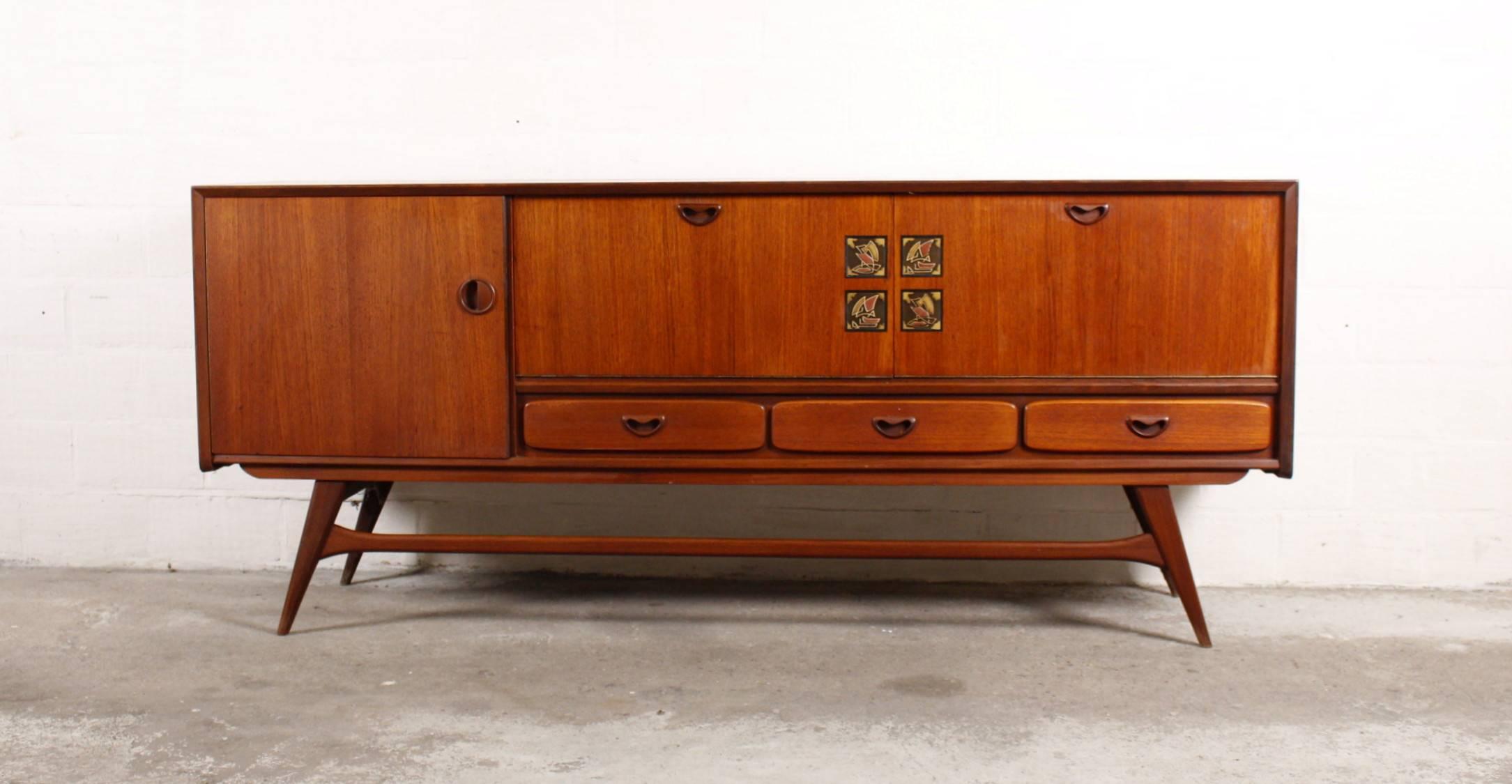 Sideboard of designer Louis Van Teeffelen for Wébé.
The sideboard is full teak wood.
With a nice accent by four ceramic tiles in the middle of the cabinet.
The cabinet is in very good condition.