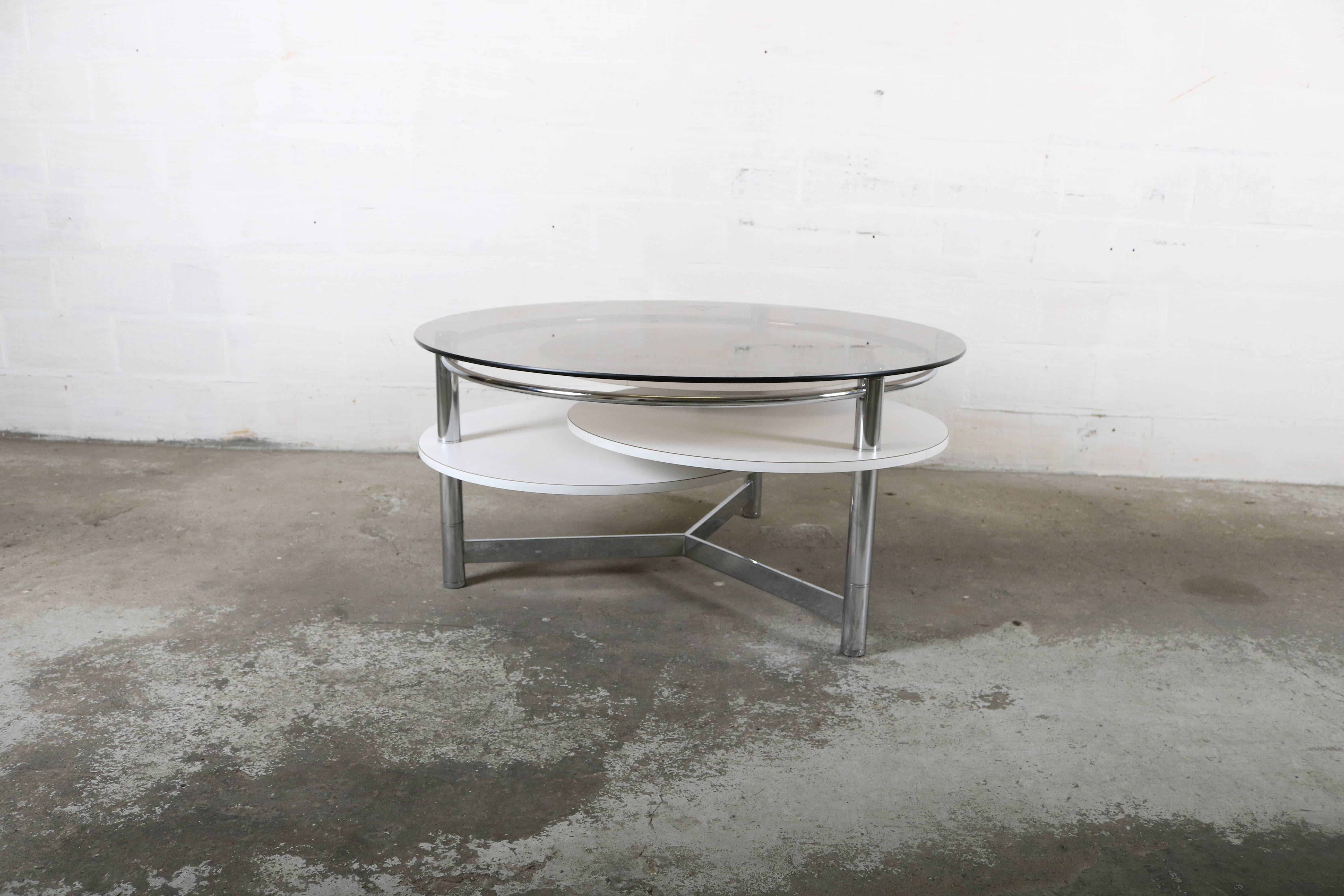 Design coffee table with rotating table tops.
Made of chrome metal base and white formica table tops.
The top table is made of glass.